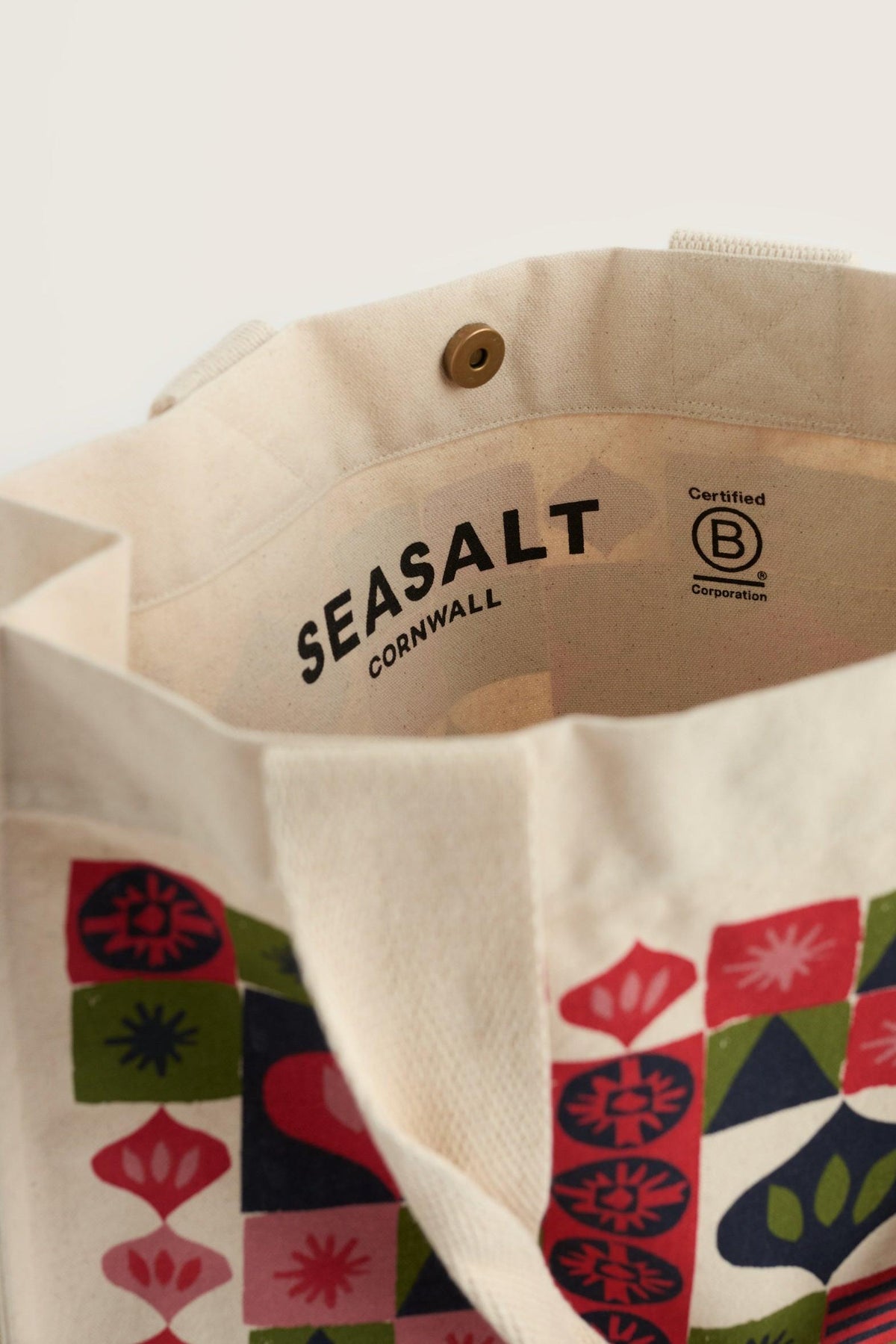 Open Seasalt Cornwall canvas reusable shopping bag with colorful festive geometric print and B Corp logo inside.