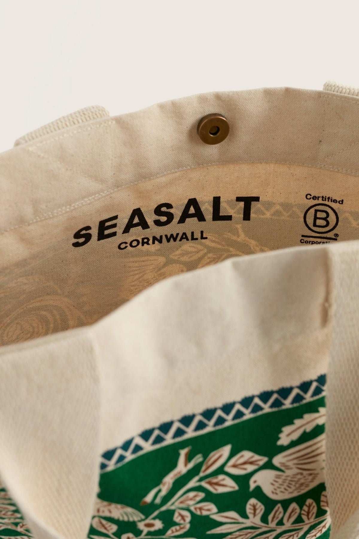 Interior view of a Seasalt Cornwall cream canvas shopping bag with a snap button and B Corp logo.