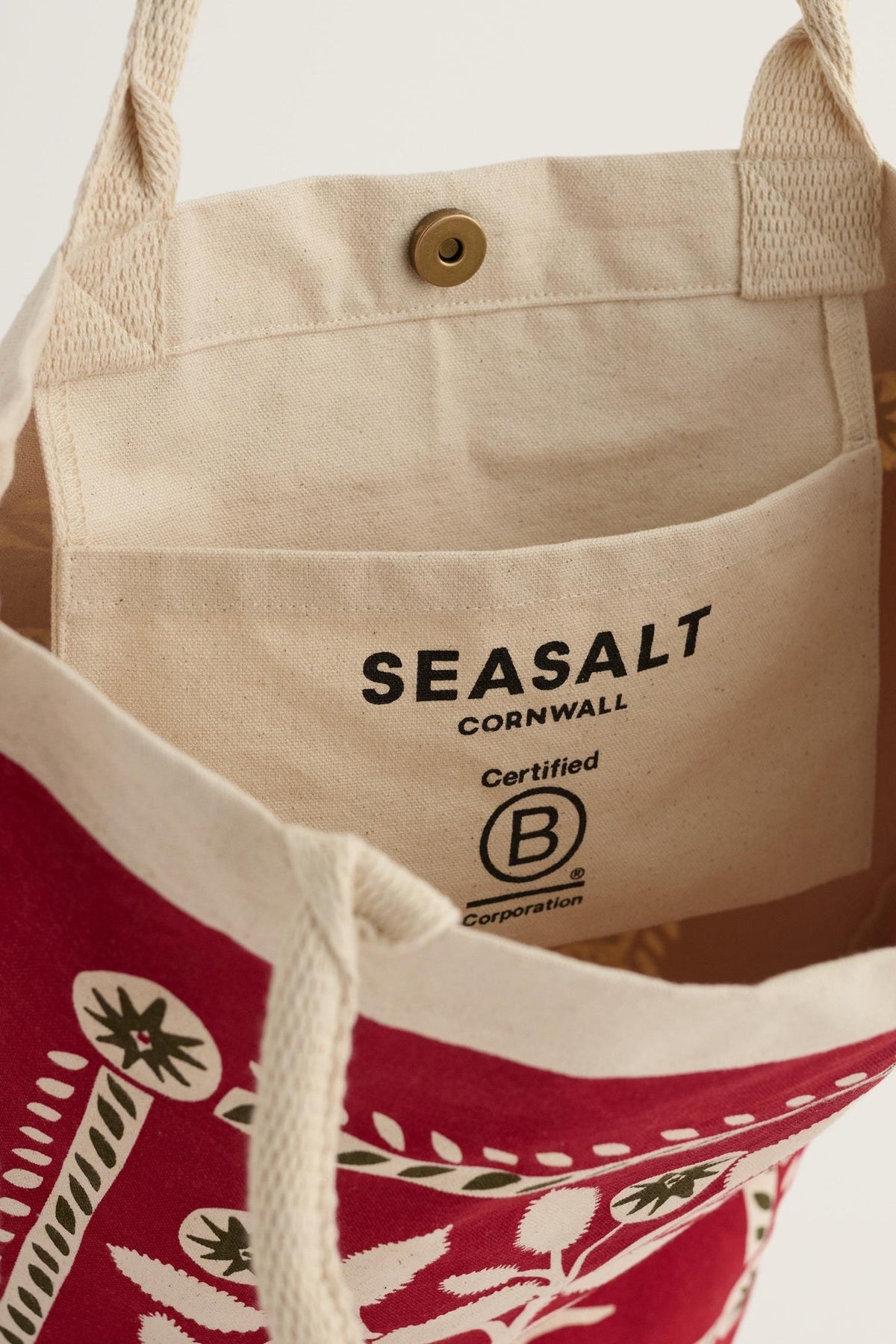 Open Seasalt Cornwall canvas shopping tote with a red Christmas tree print and interior Certified B Corporation branding.