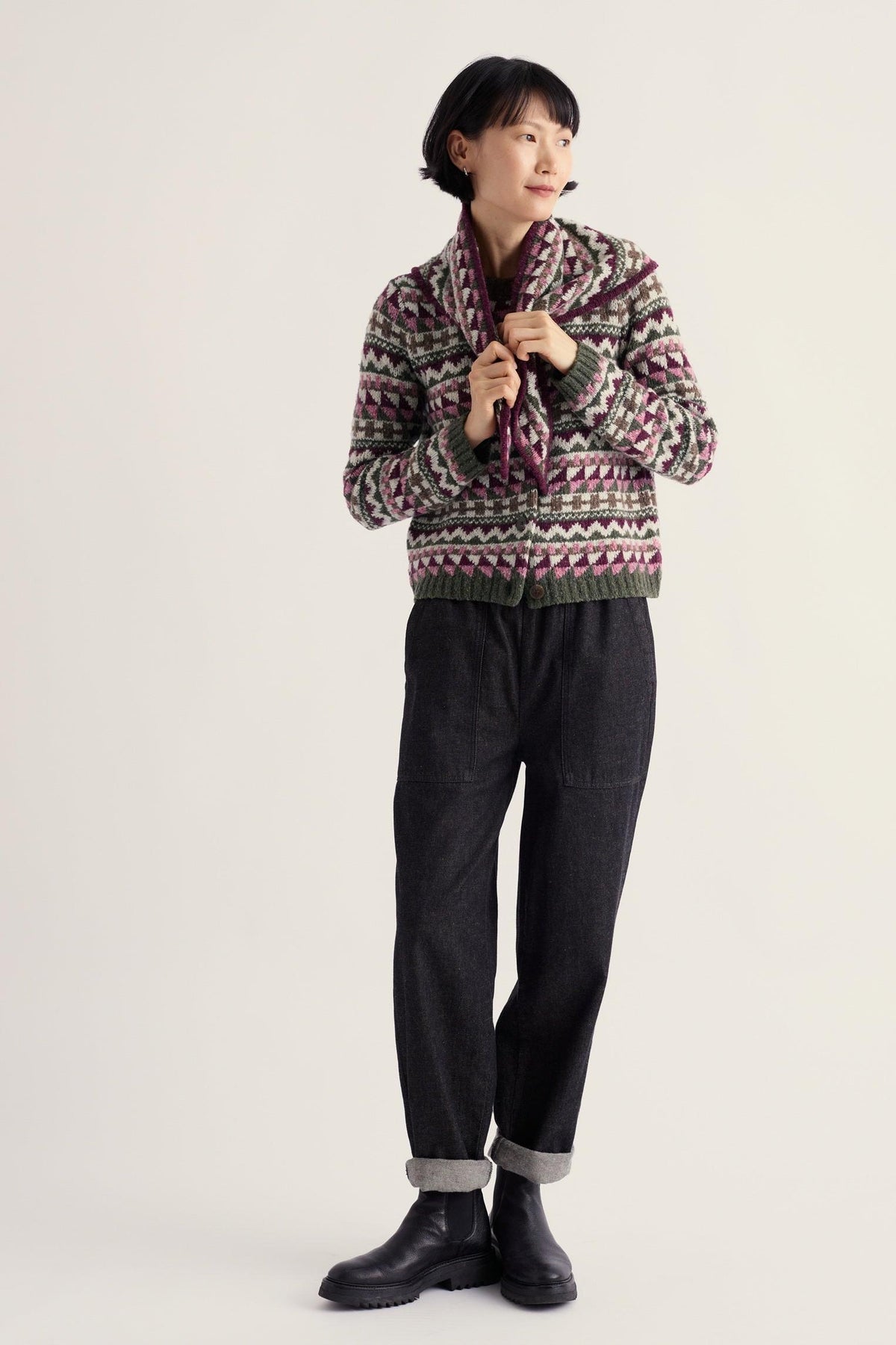A woman wearing a Seasalt Cornwall patterned fairisle merino wool winter cardigan with dark trousers.