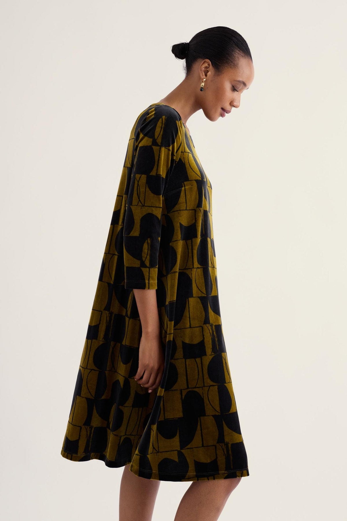 Model wearing a Seasalt Cornwall geometric print velvet dress on a plain background.