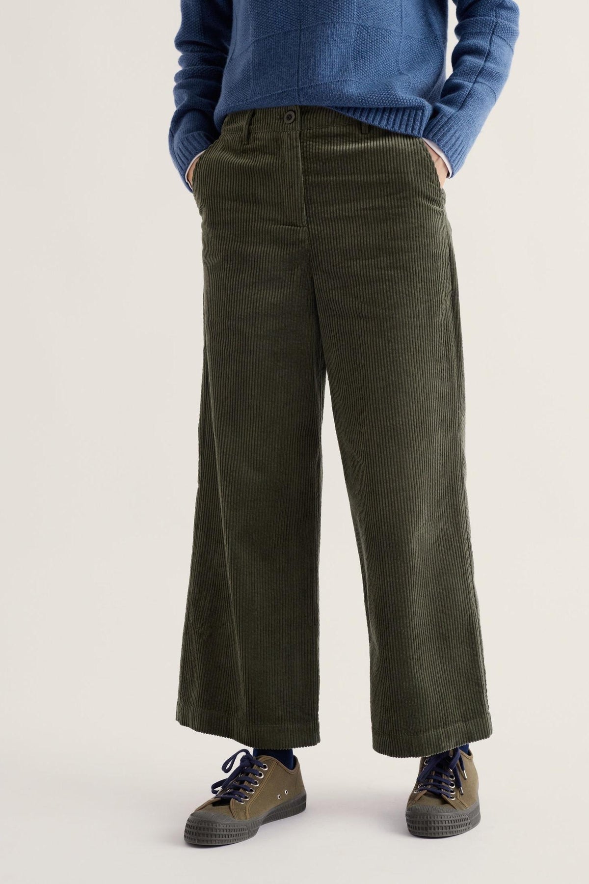 A model wearing green organic cotton cropped cord trousers from Seasalt Cornwall paired with a blue sweater.