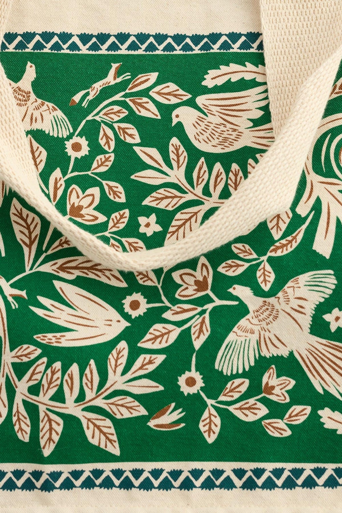 A close-up of a Seasalt Cornwall green canvas shopping bag featuring a cream-colored bird and floral print pattern.