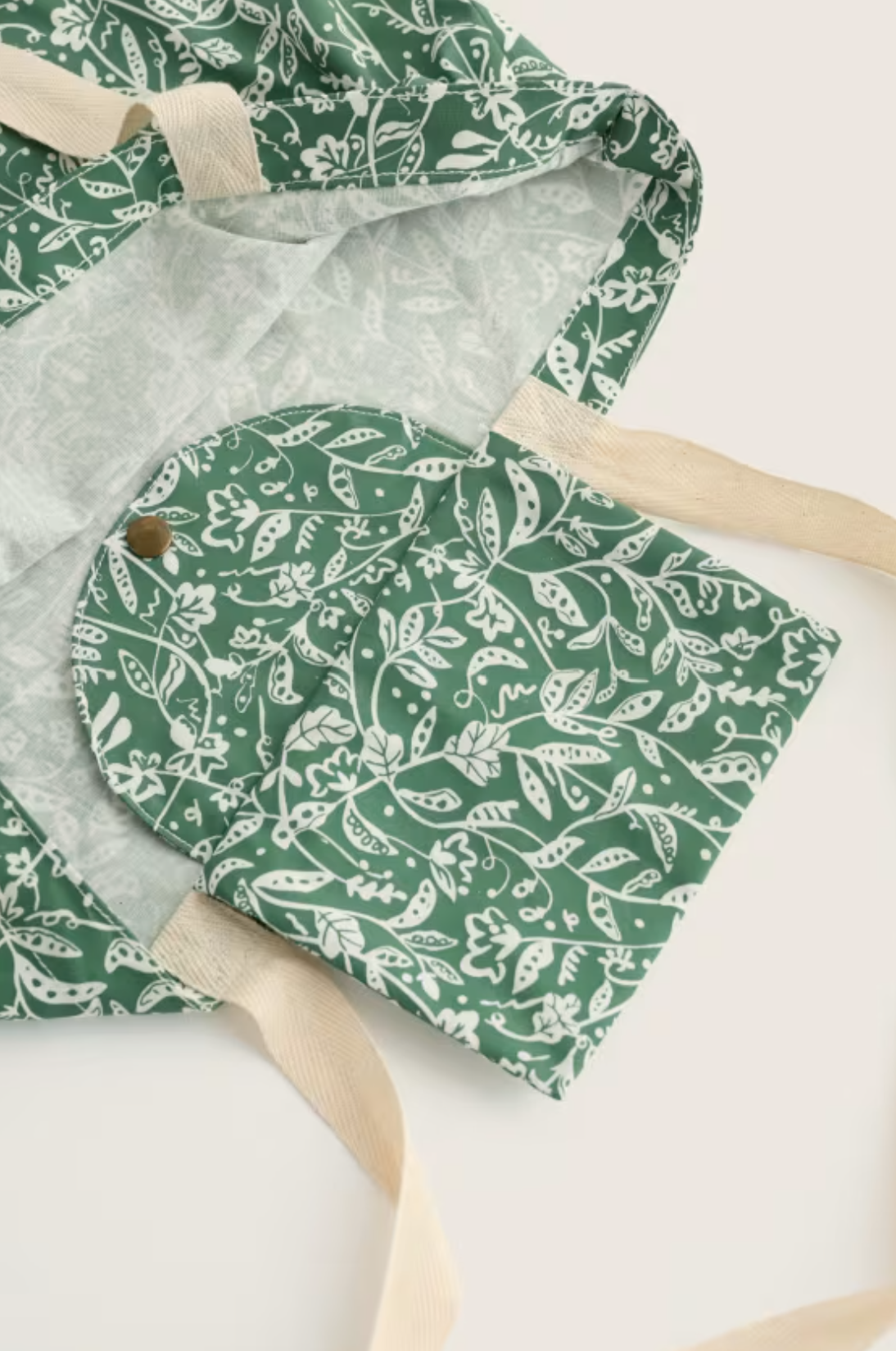 Seasalt Cornwall green floral cotton foldaway shopping bag with cream handles on a plain white background.