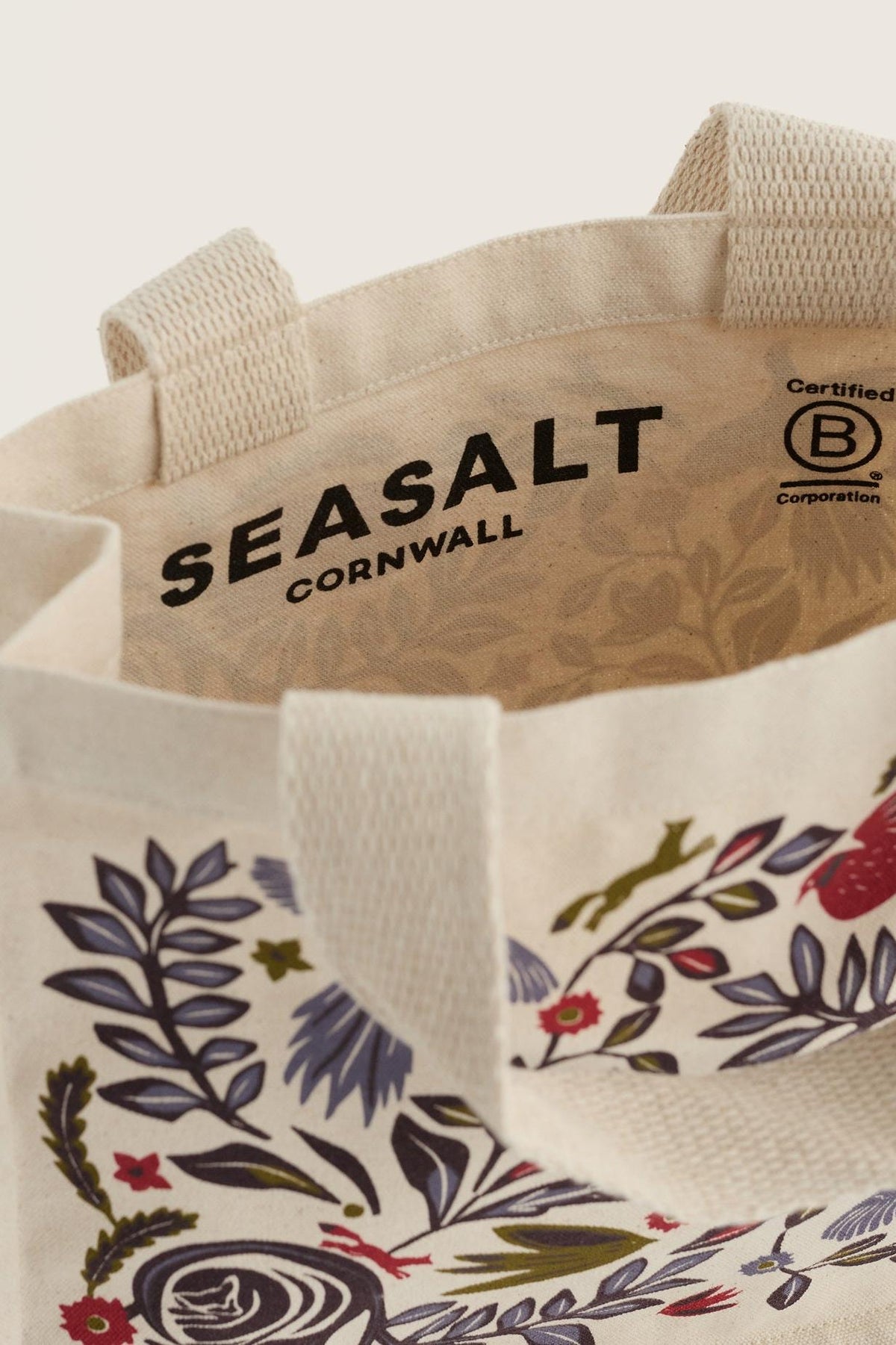 Open view of a Seasalt Cornwall organic cotton canvas shopping bag with floral print and B Corp logo.