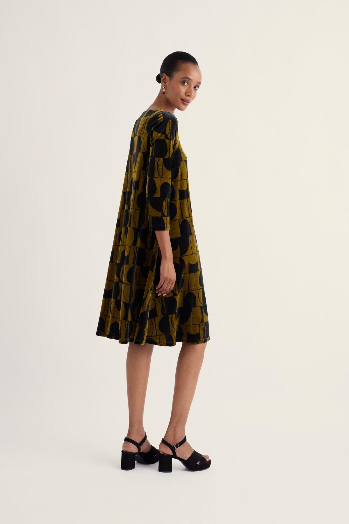 Model wearing a Seasalt Cornwall geometric print velvet dress on a plain background.