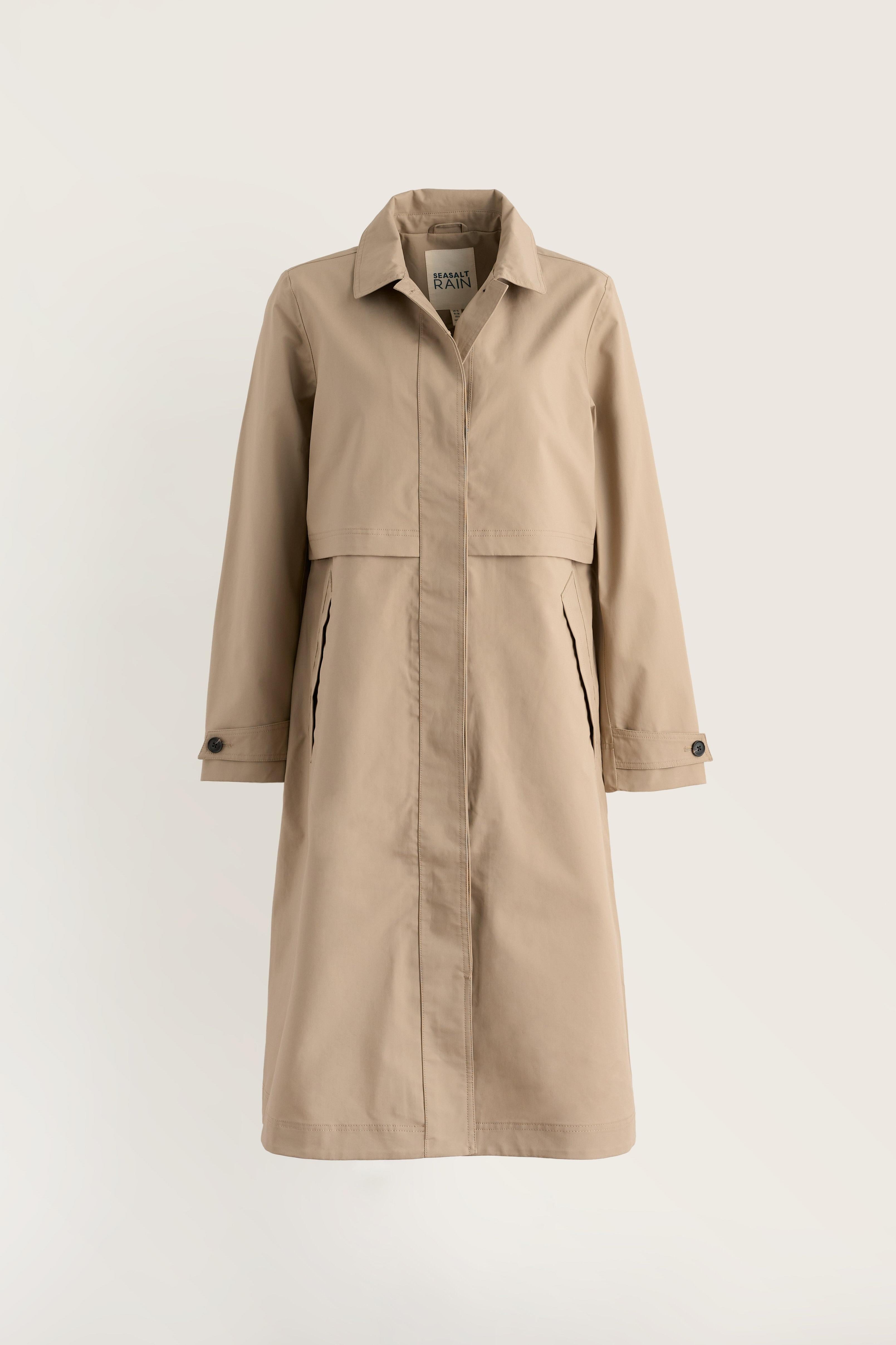 A beige trench coat with a pointed collar, front button closure, and side pockets, displayed on a clean, light off-white background.