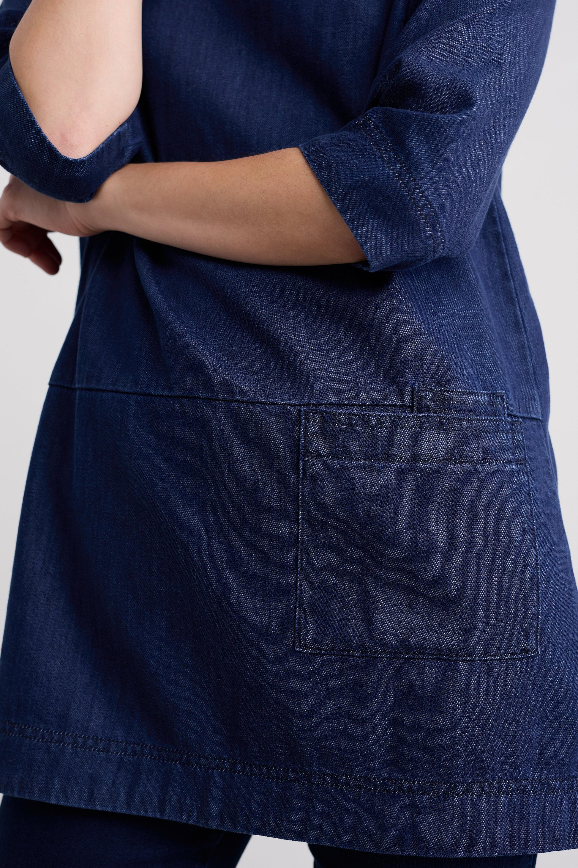 Navy blue denim dress with rolled-up sleeves on a light gray background