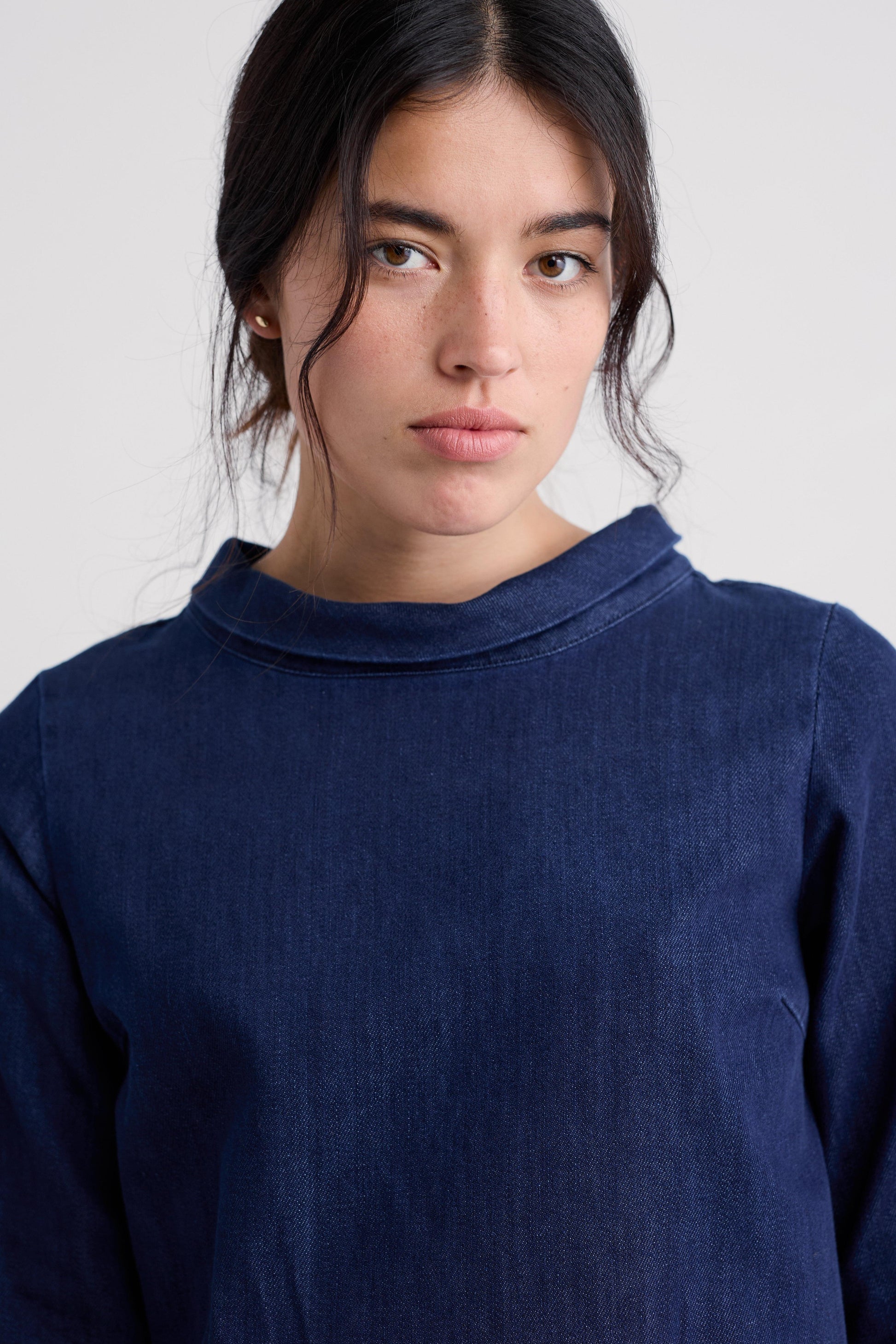 Person wearing a navy blue organic cotton tunic against a plain background