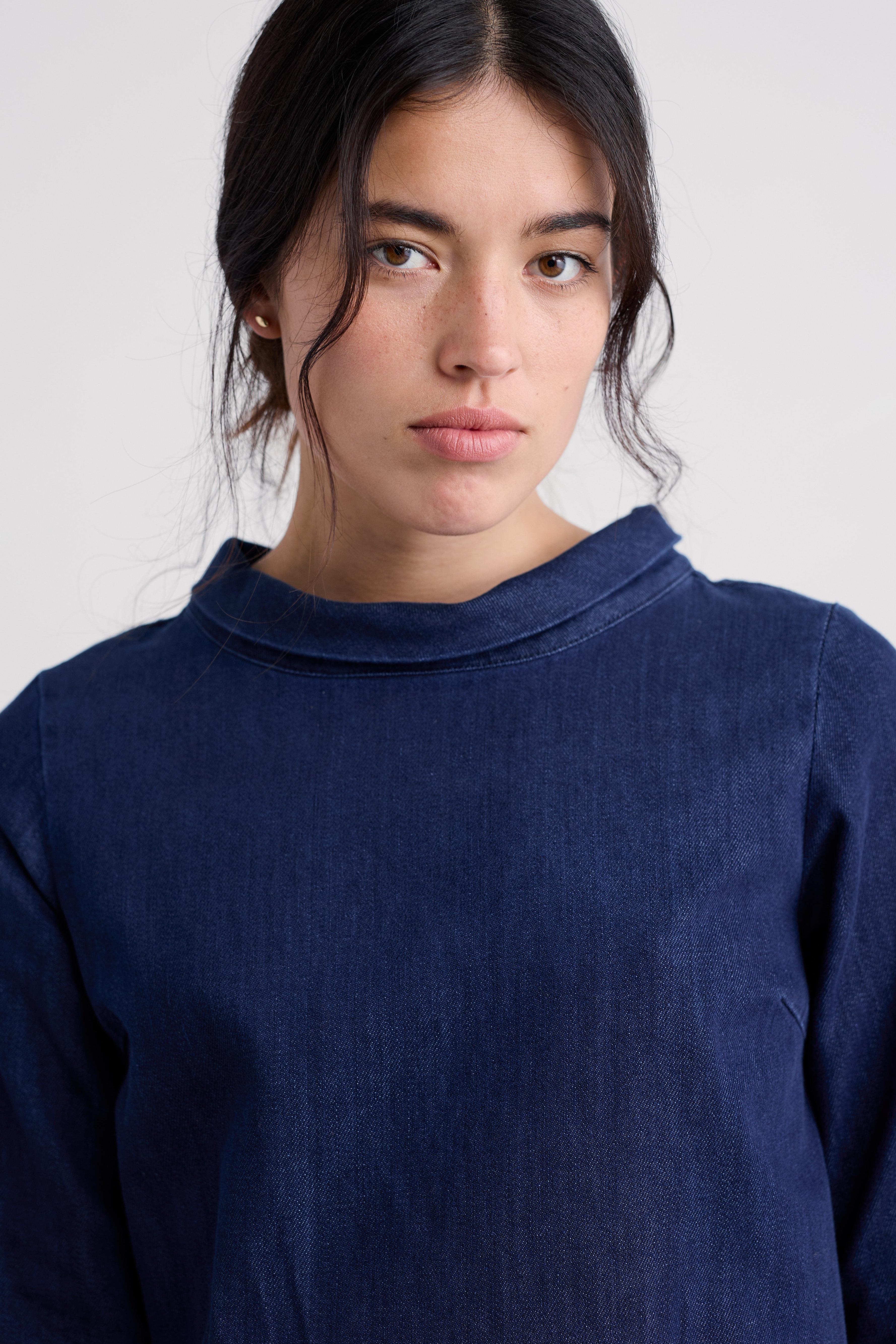 Person wearing a navy blue organic cotton tunic against a plain background