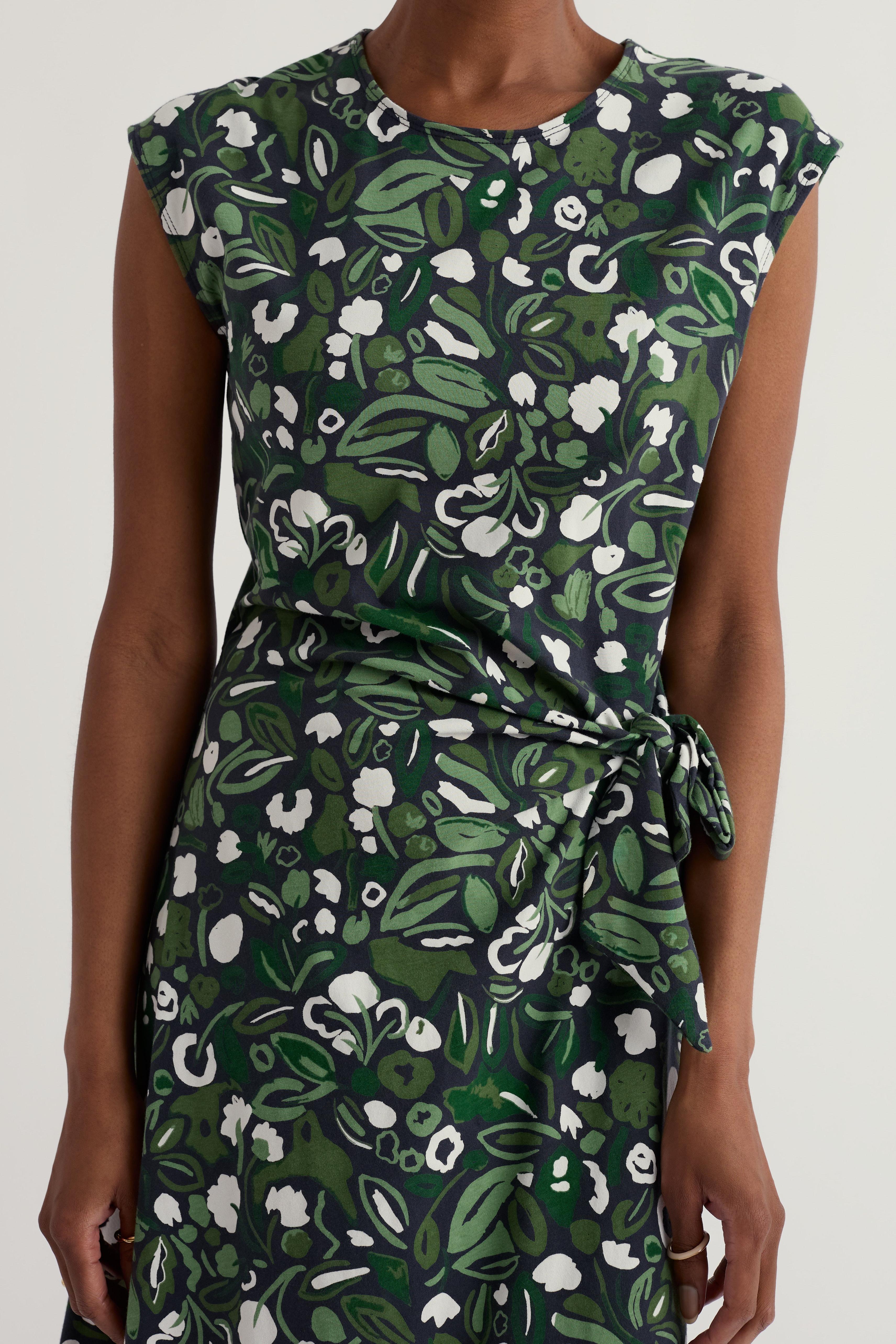 Green organic cotton floral dress worn by a model on a white background