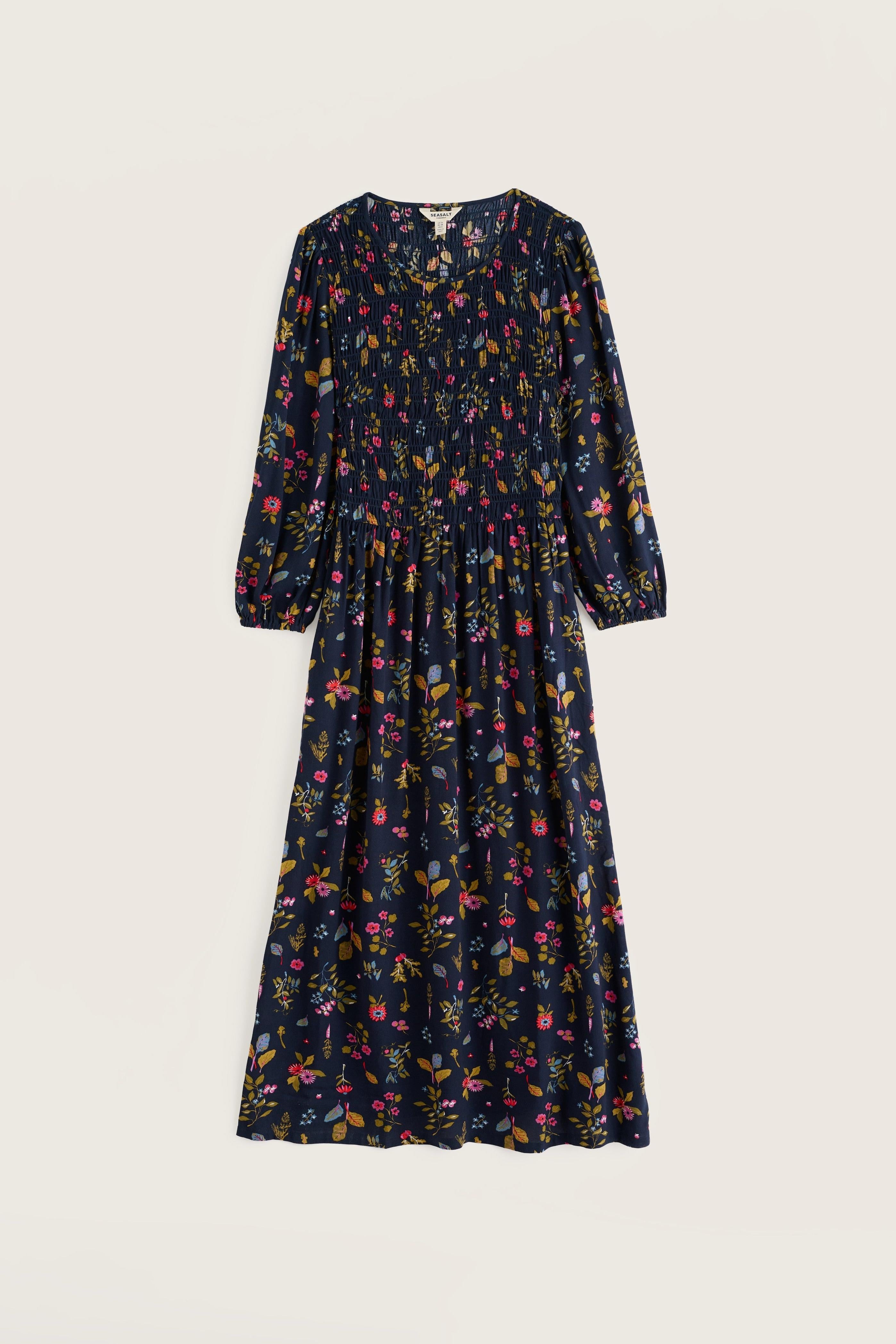A long-sleeved midi dress with a dark navy blue base and an all-over multicolor floral print, shown flat against a light beige background.