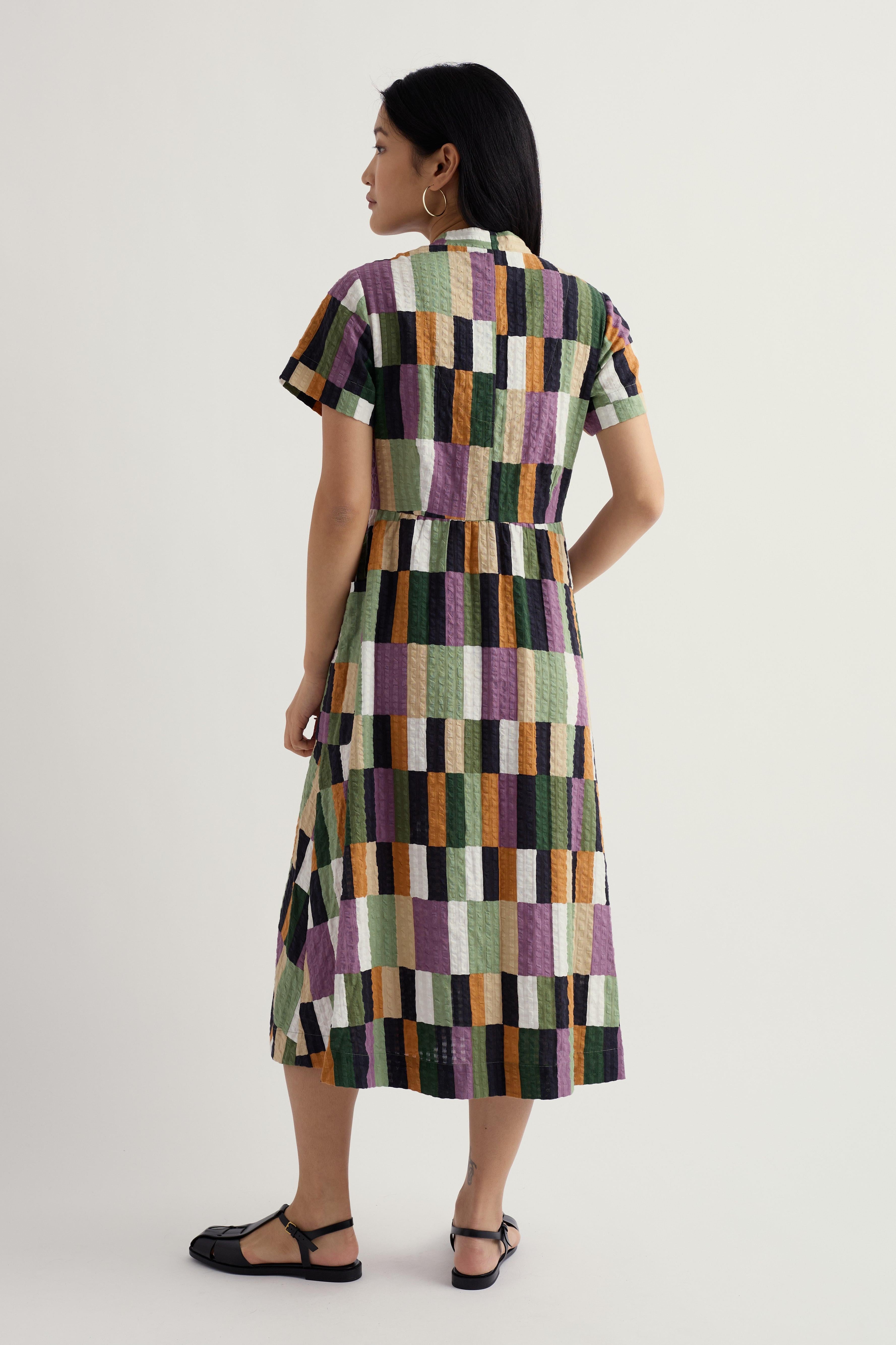Woman wearing a colourful geometric patterned dress on a white background