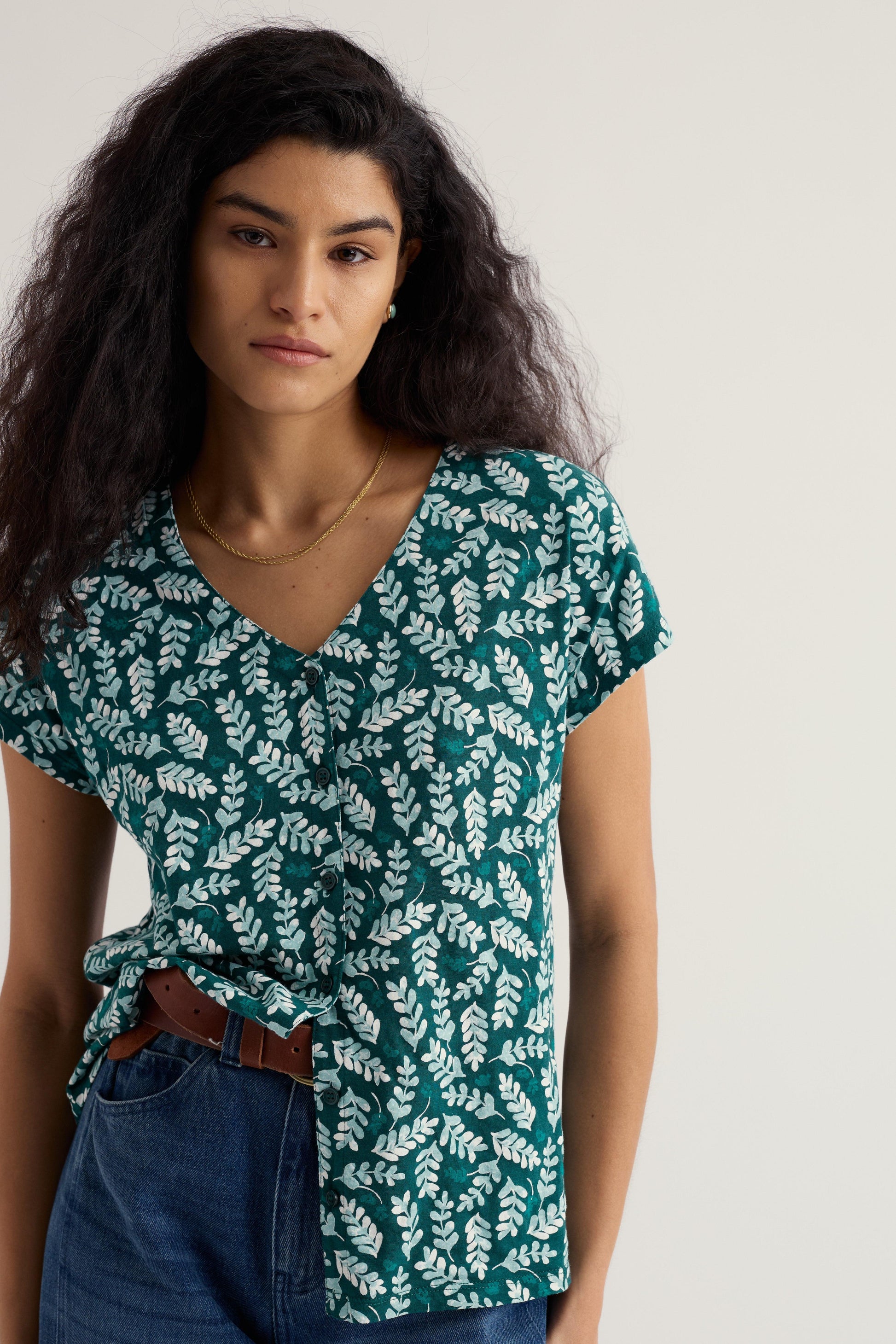 Model wearing a green leaf-patterned shirt against a white background