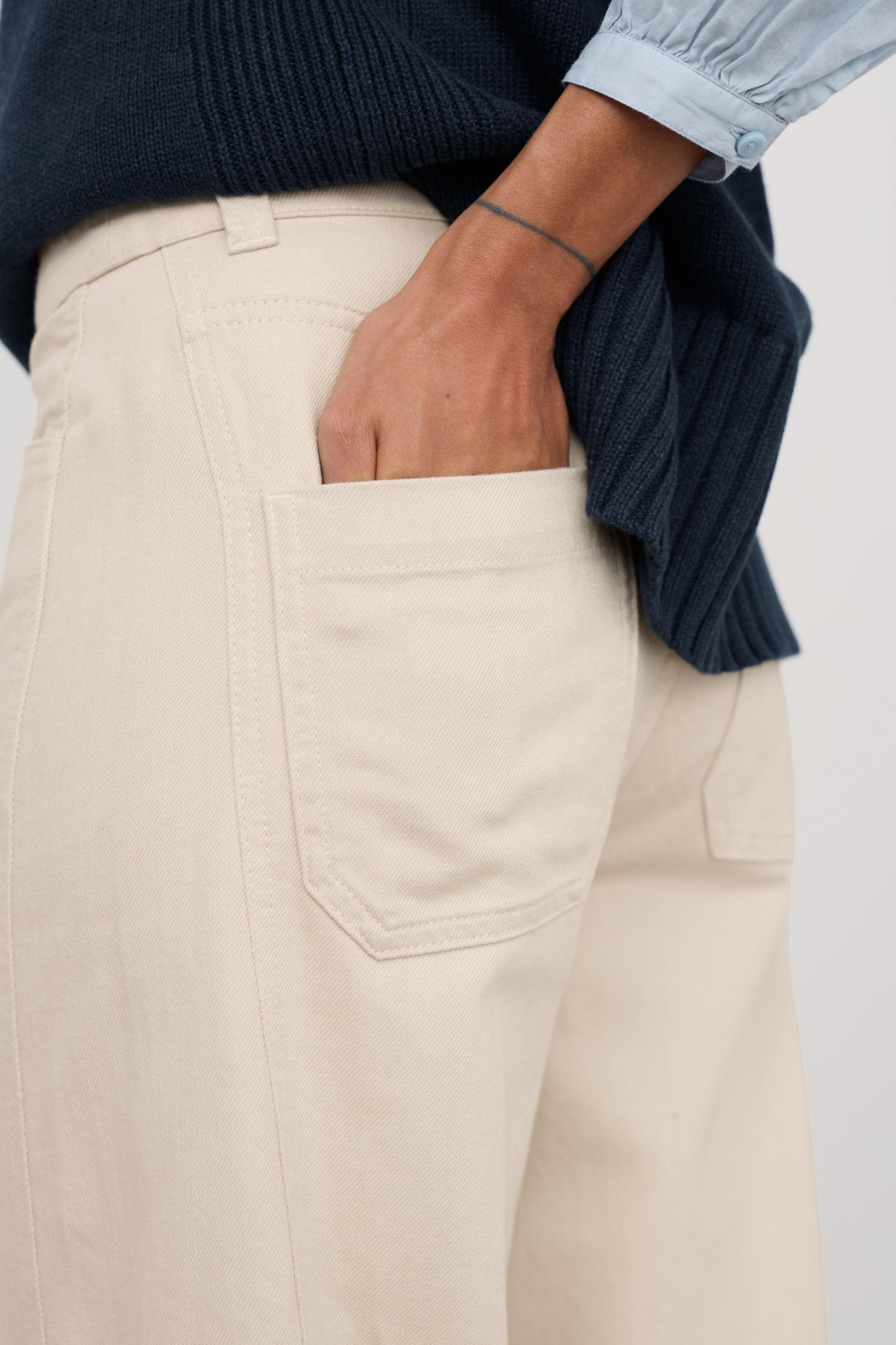 Beige pants with a person wearing a navy sweater and light blue shirt.