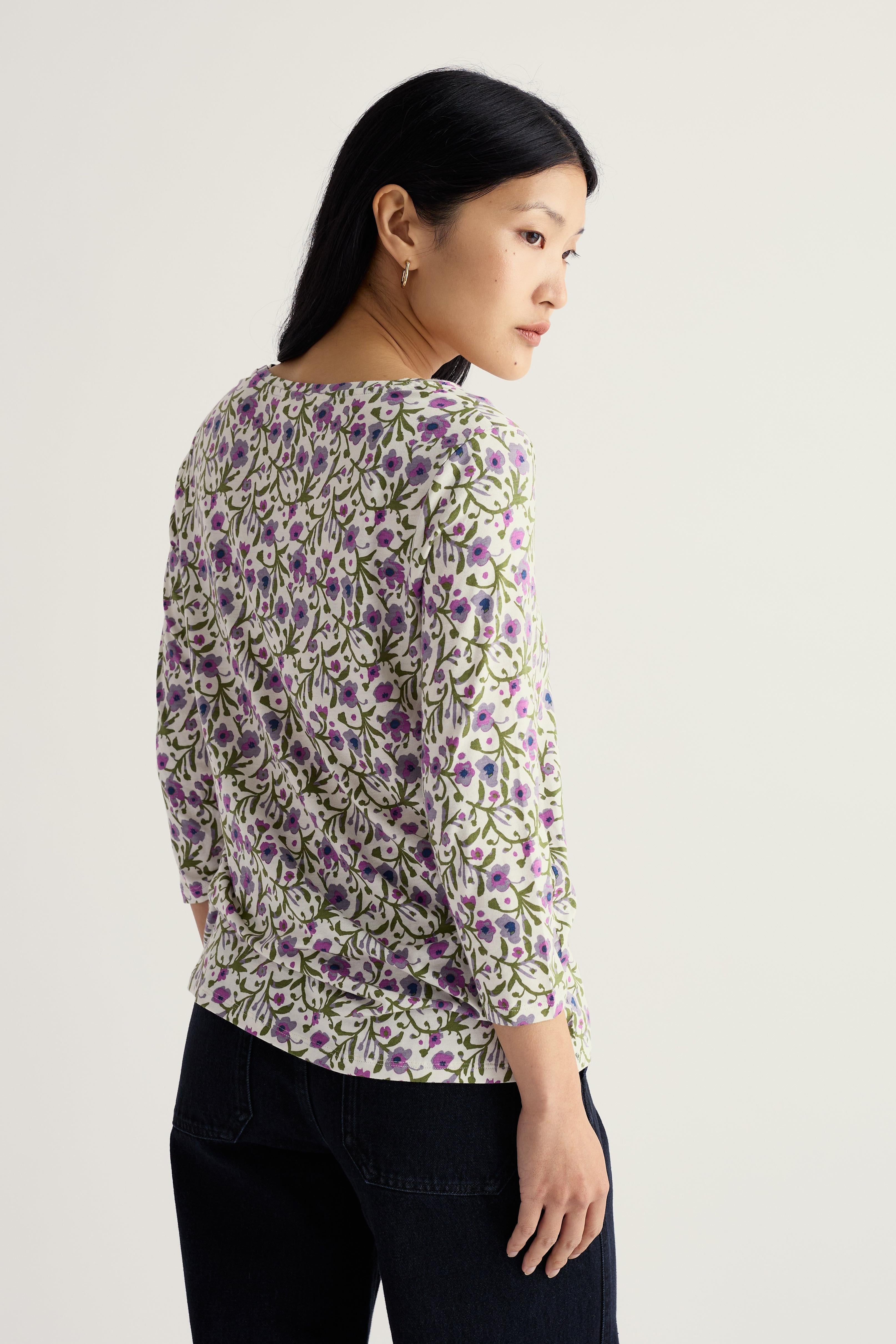 Woman wearing a floral organic cotton blouse with a neutral background