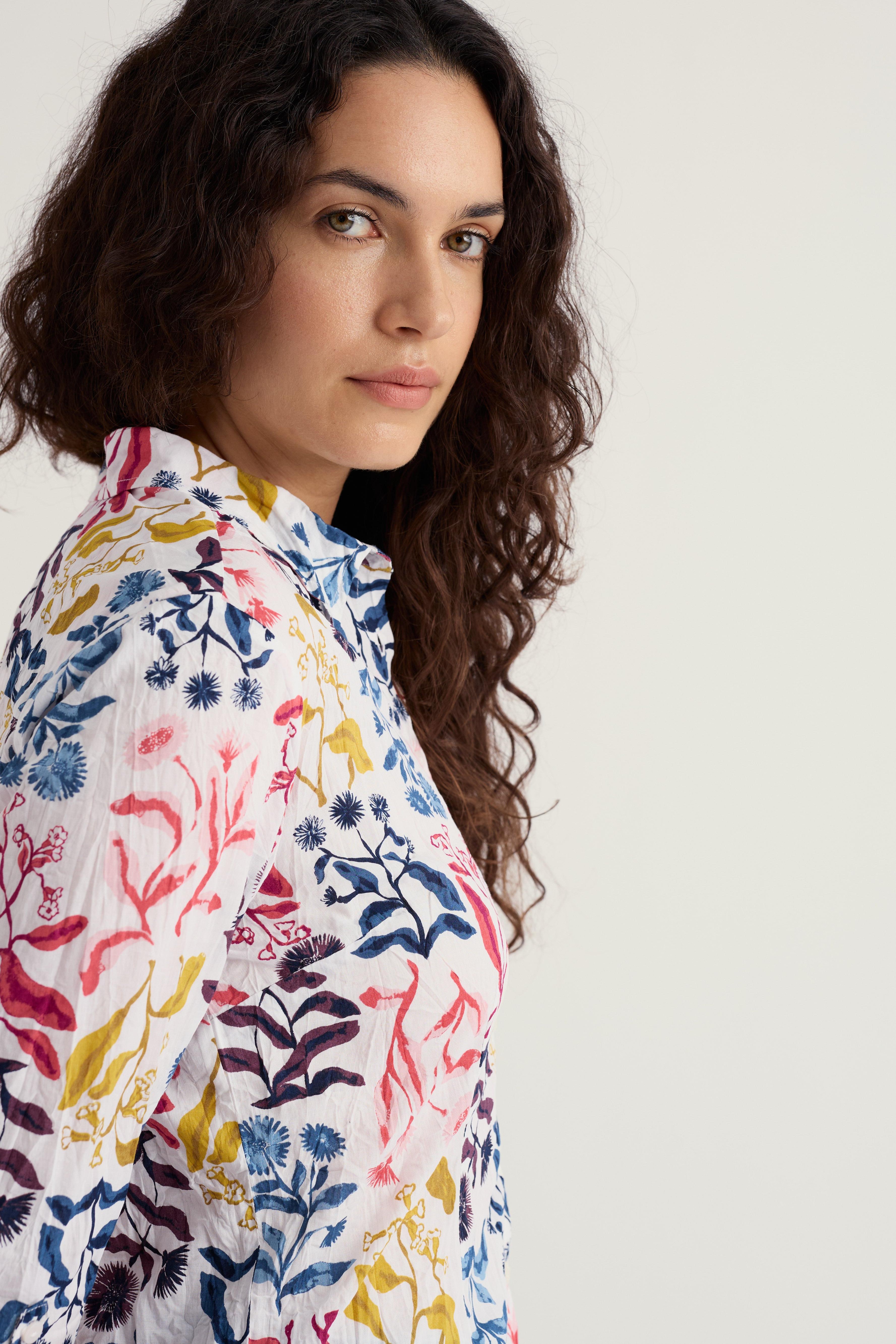 Woman wearing a Seasalt Cornwall floral shirt against a plain background