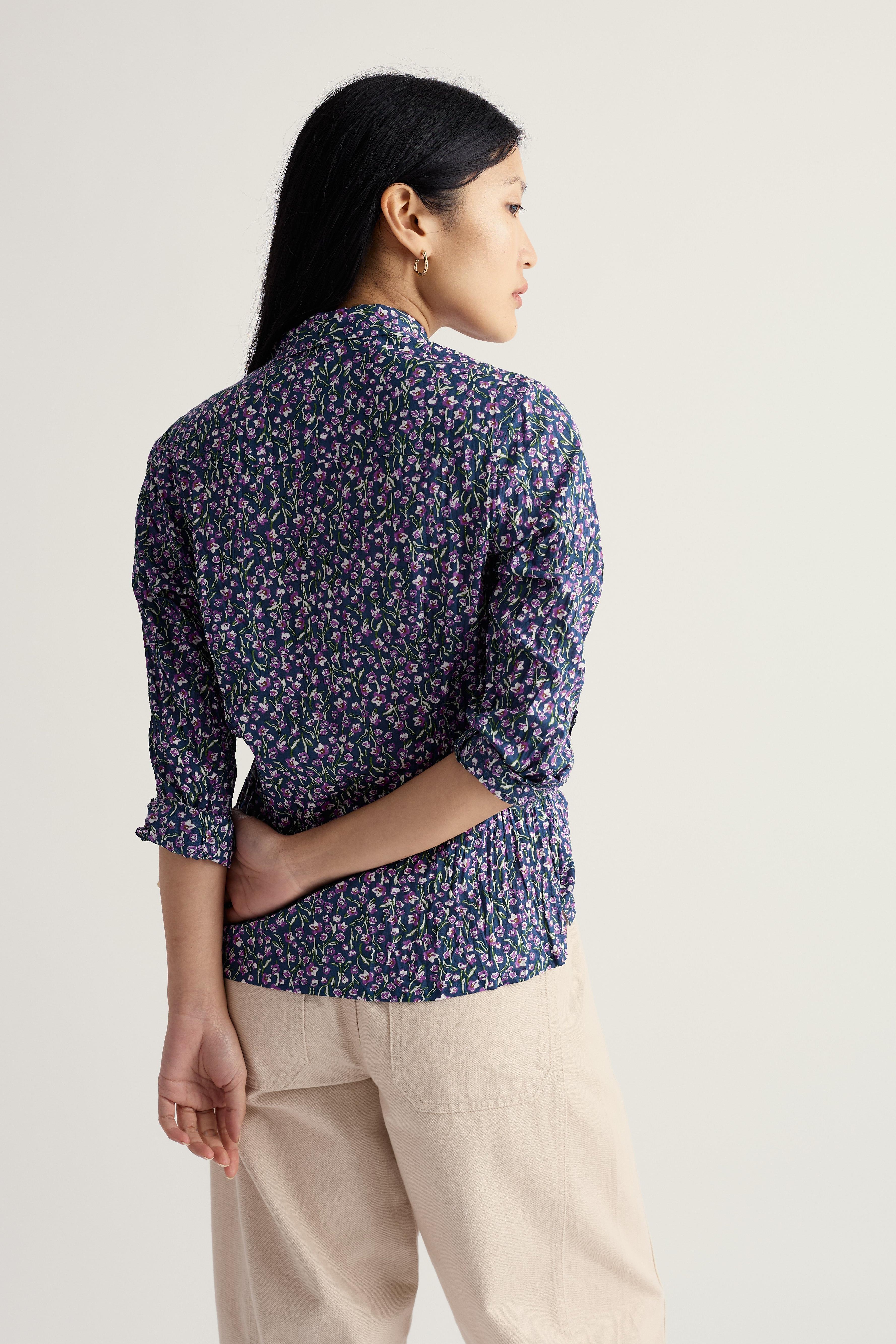 Woman wearing a patterned organic cotton shirt and beige pants on a plain background
