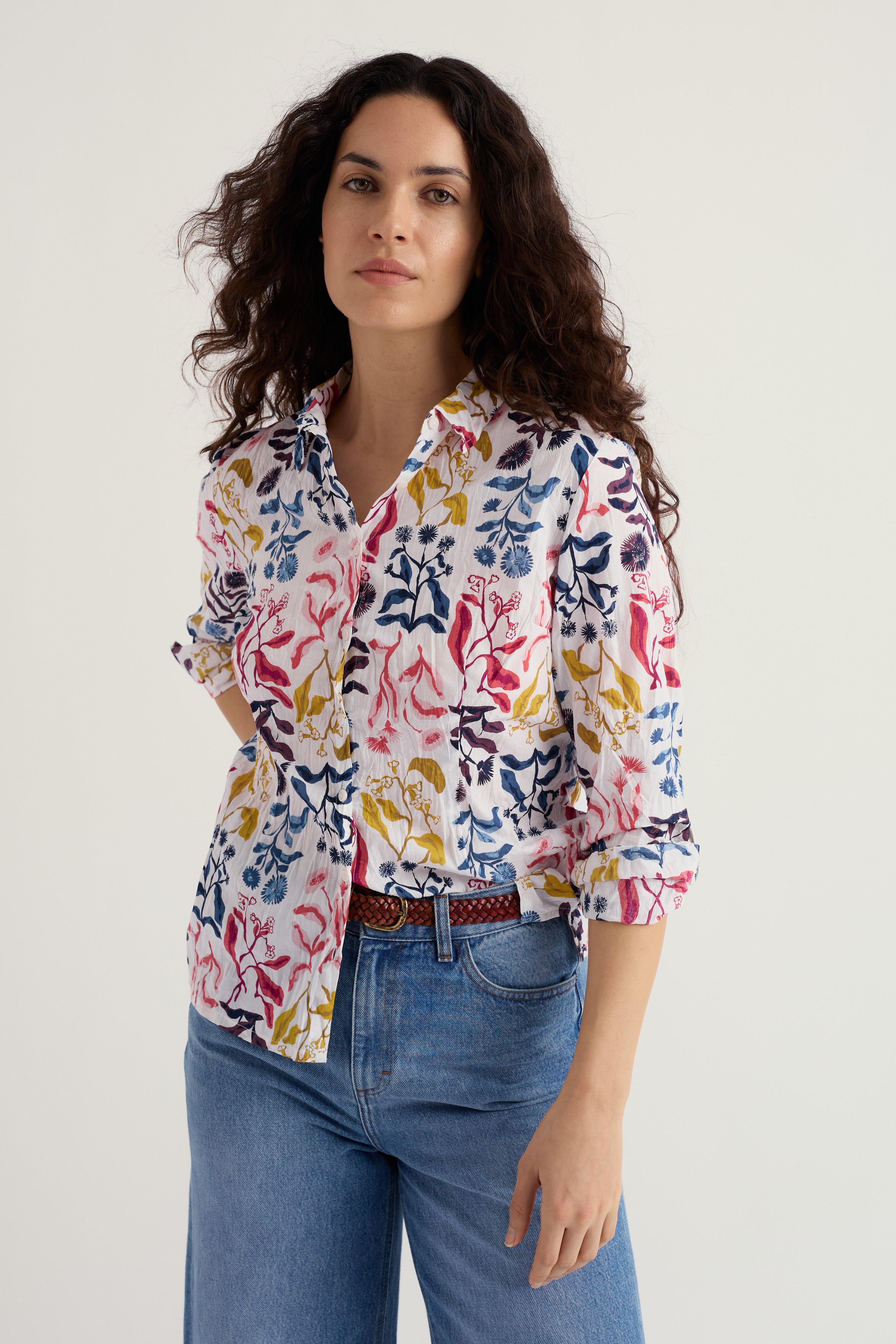 Woman wearing a patterned organic cotton shirt and blue jeans on a white background