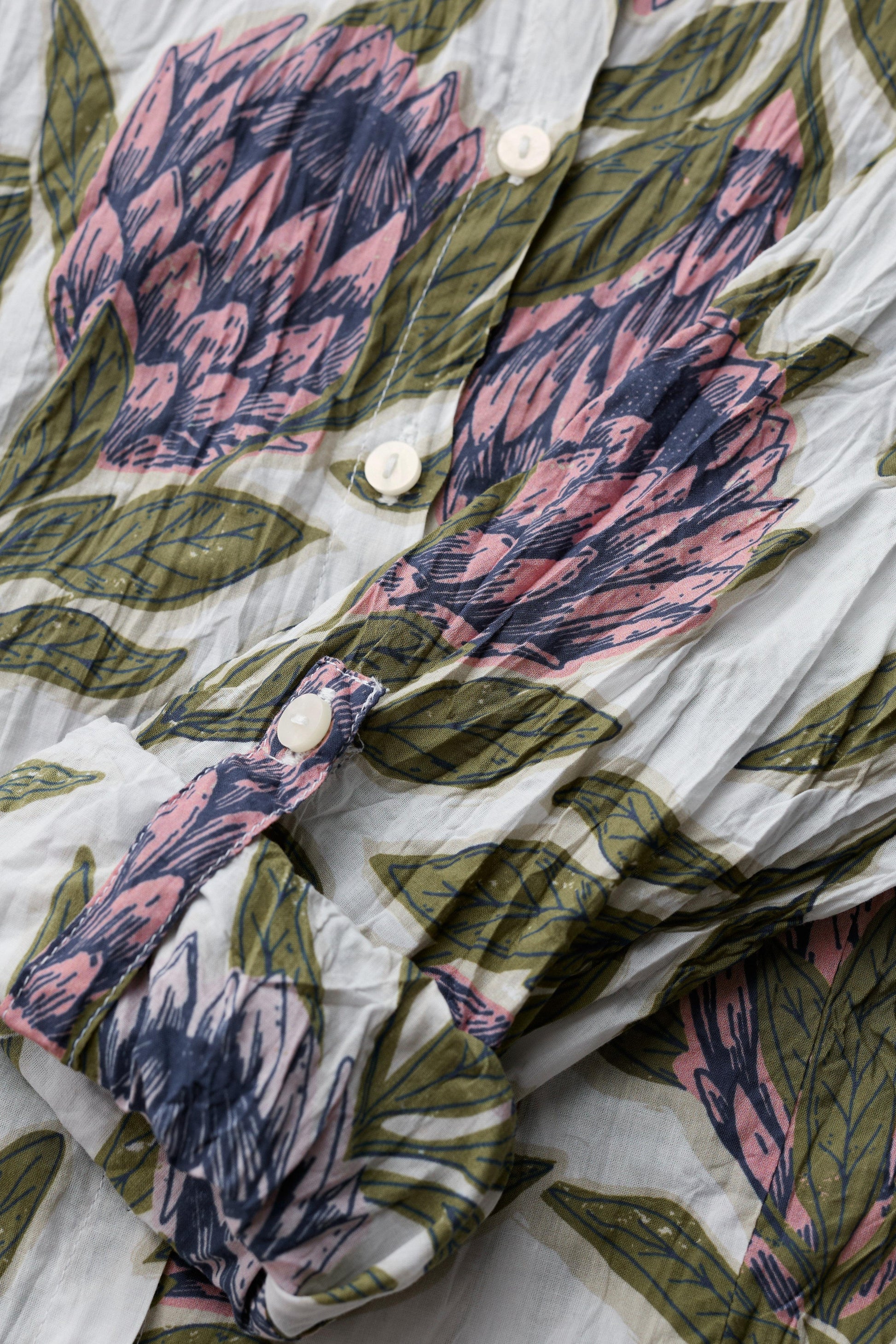 Floral patterned fabric with pink and green leaves on a white background