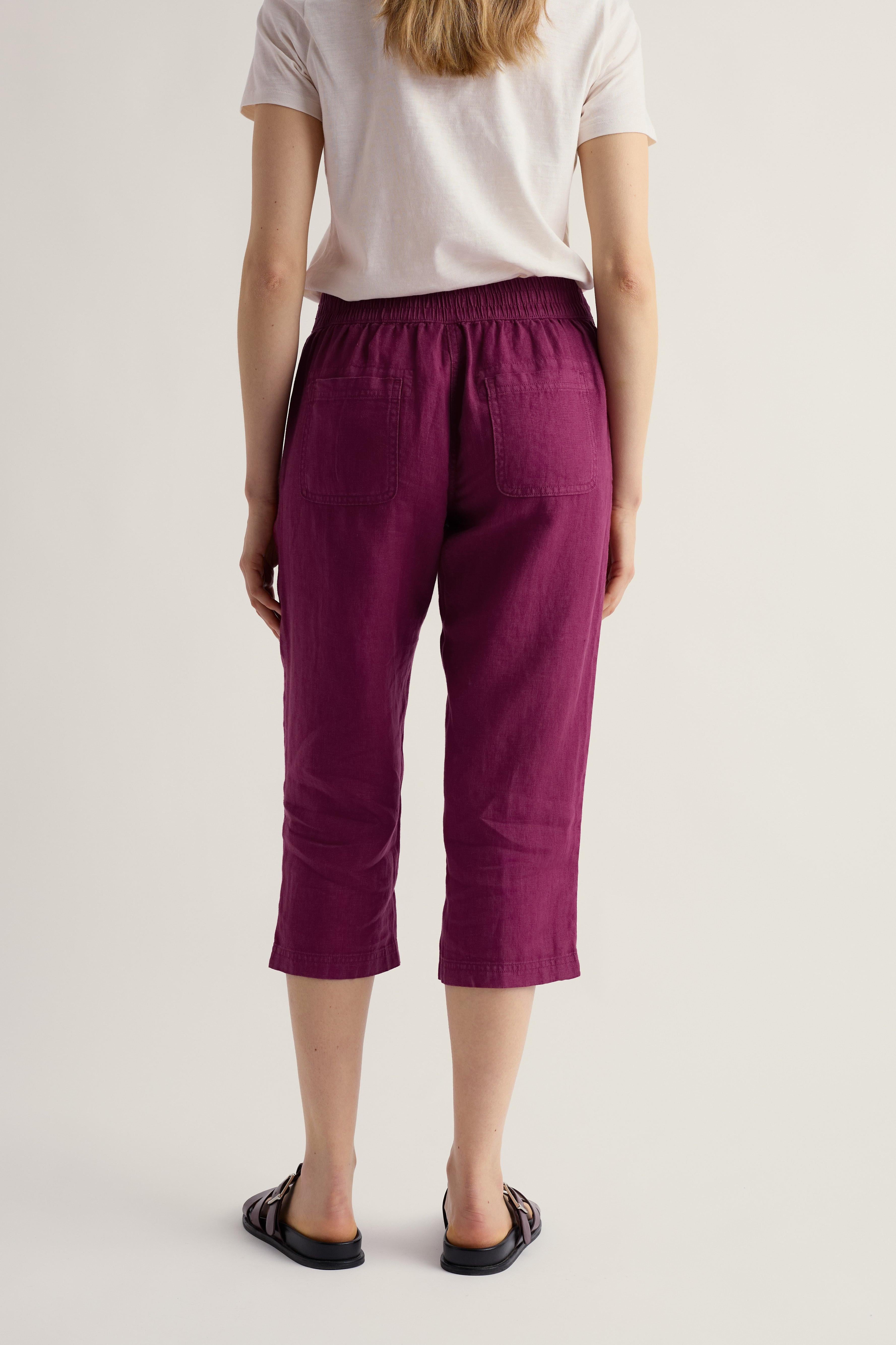 Person wearing purple cropped pants and a white shirt on a plain background