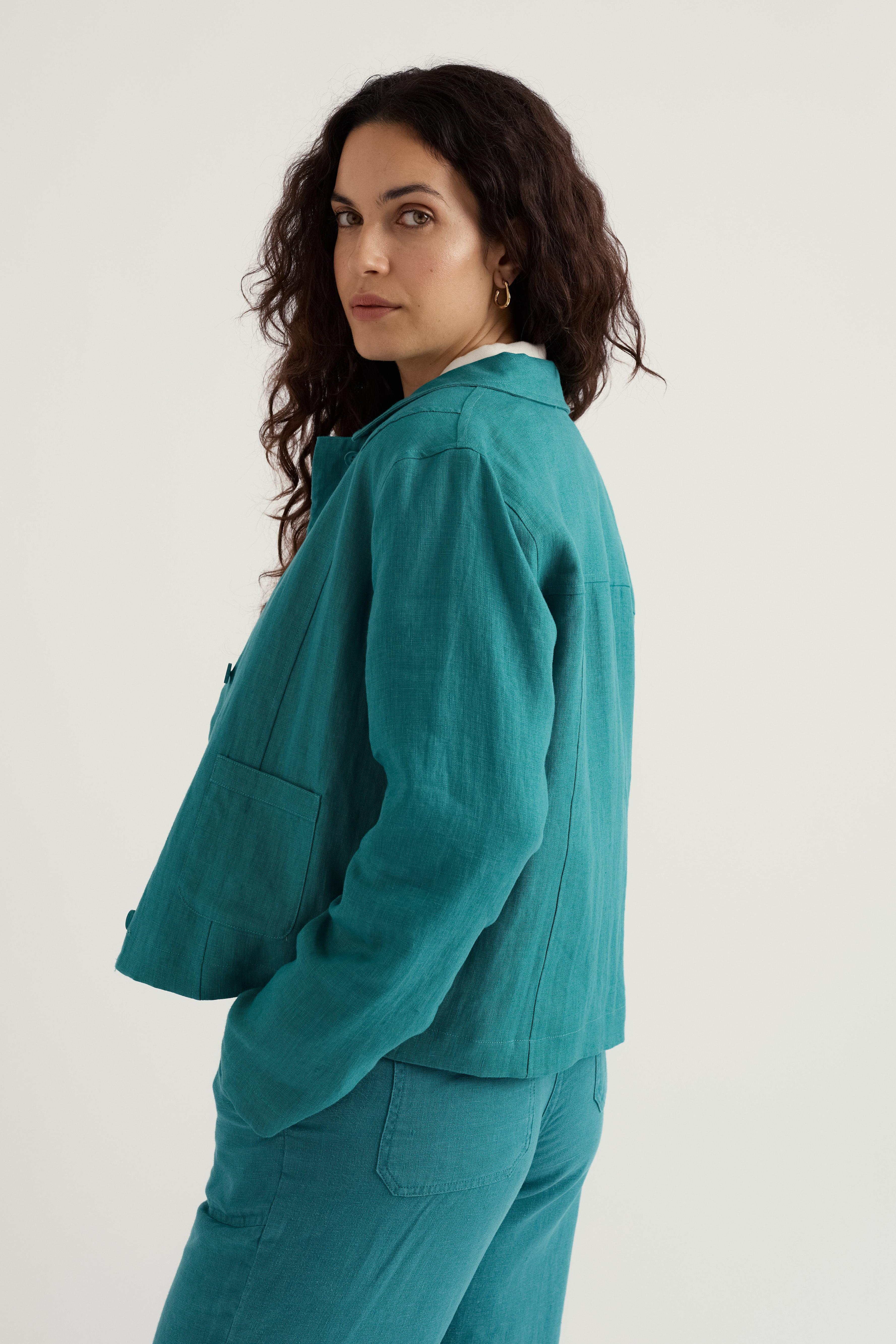 Woman wearing a teal linen outfit on a plain background