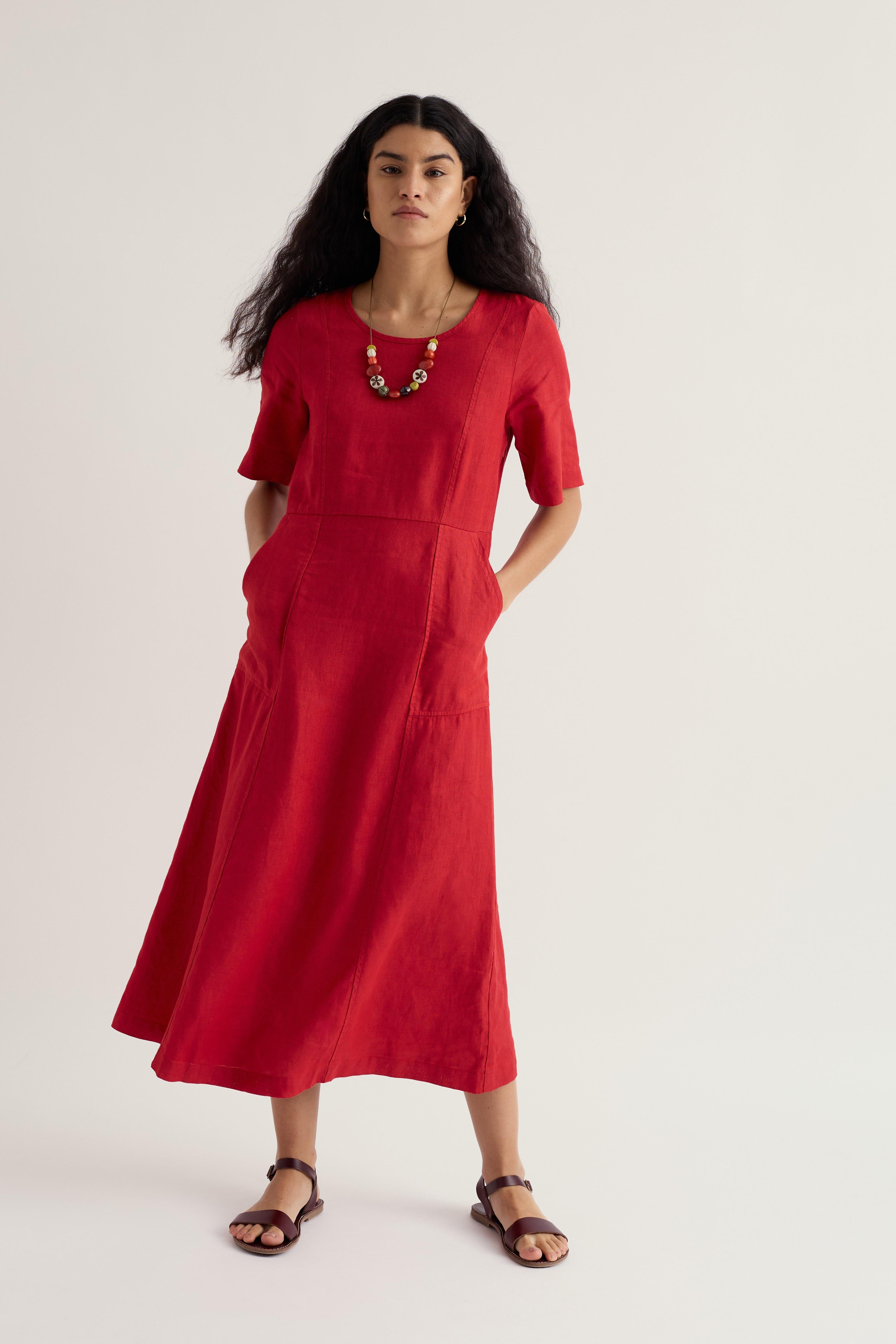Woman wearing a red linen dress on a plain background