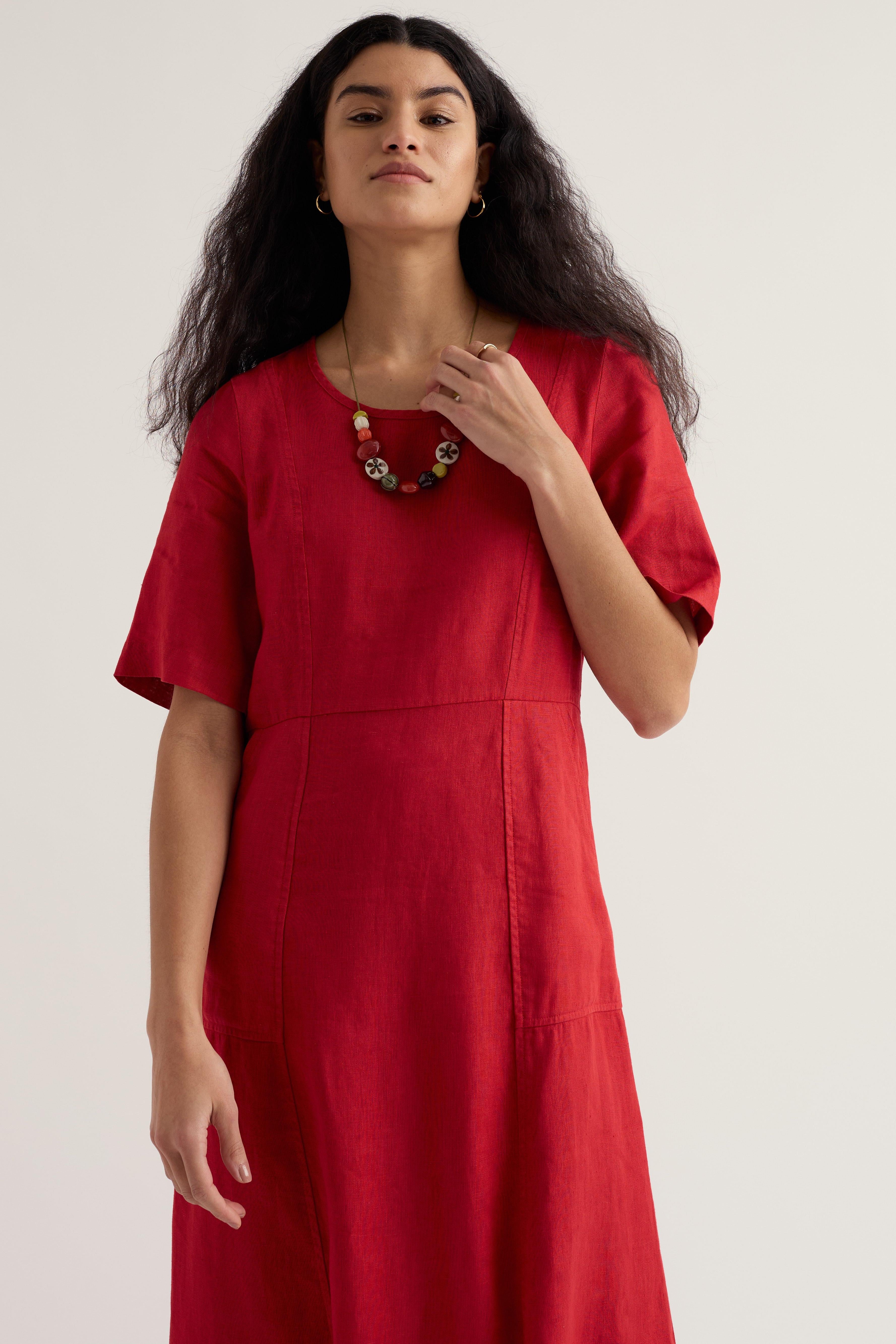 Woman wearing a red linen dress against a plain background