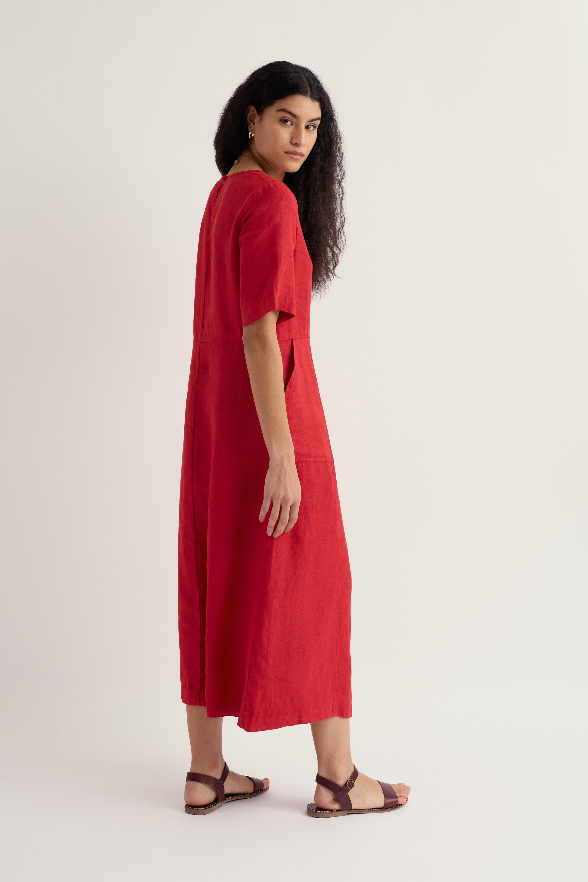 Woman wearing a Seasalt red linen dress on a white background