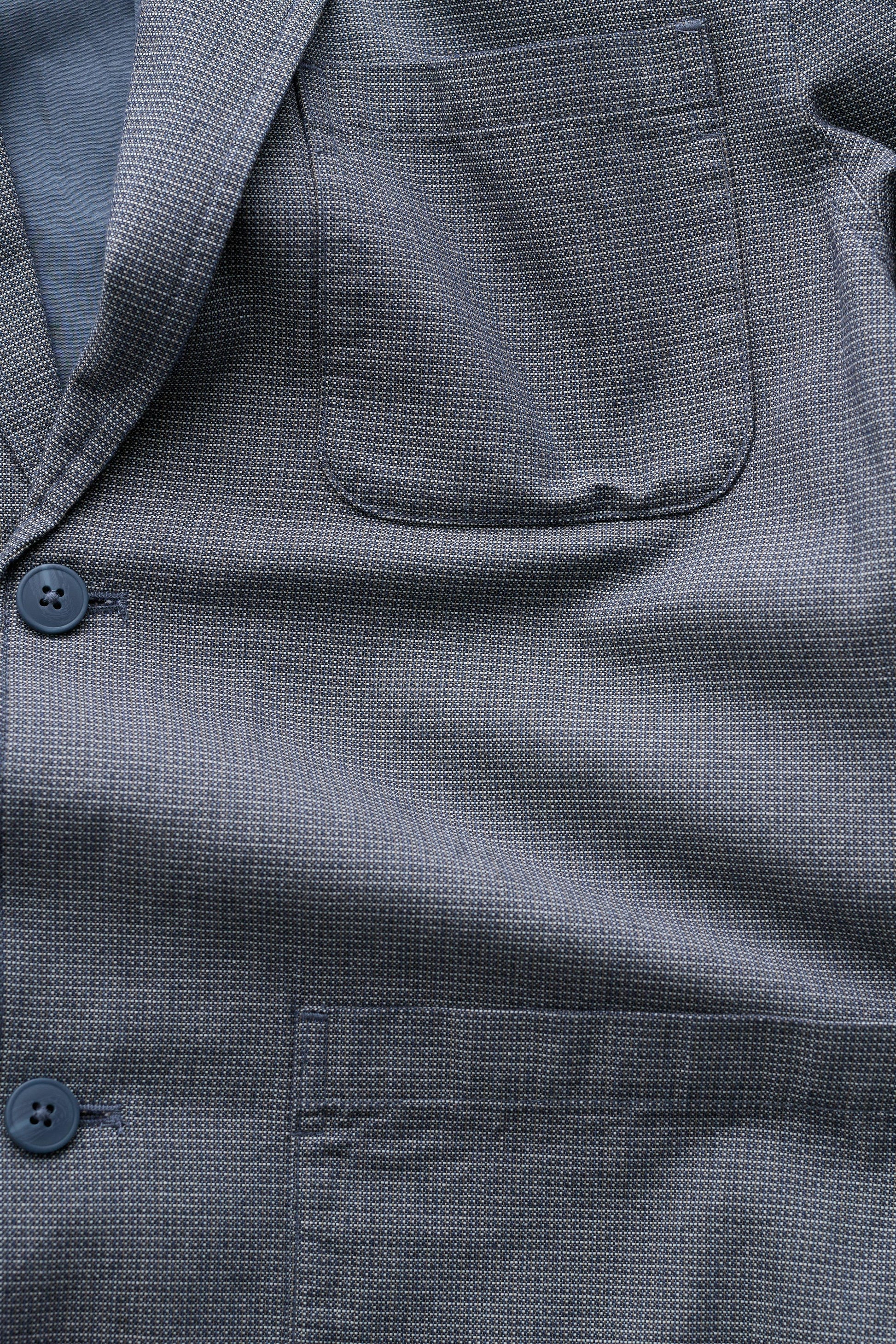 Close-up of a textured gray jacket with buttons and a pocket.