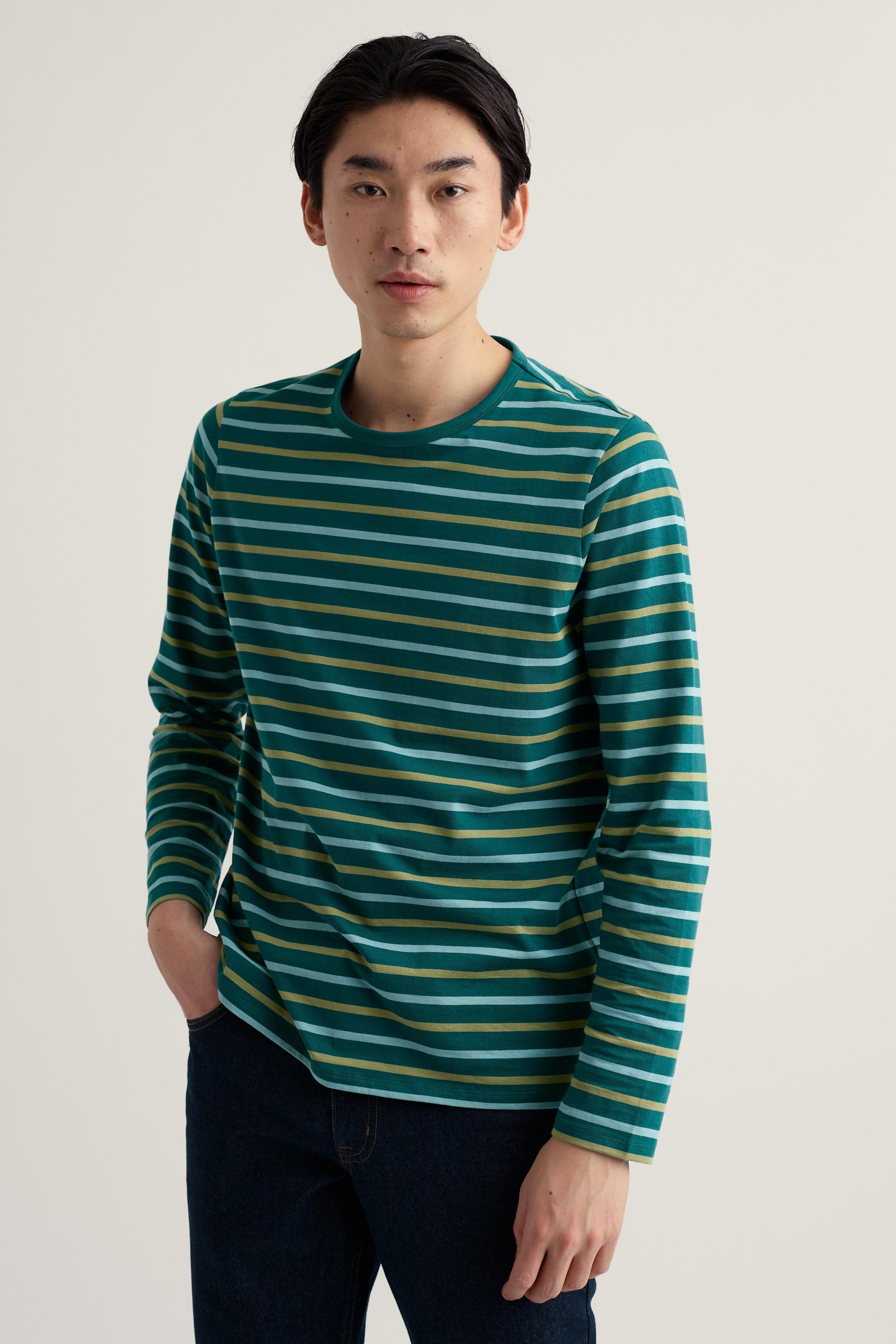 Man wearing a green and gold striped long-sleeve shirt against a plain background