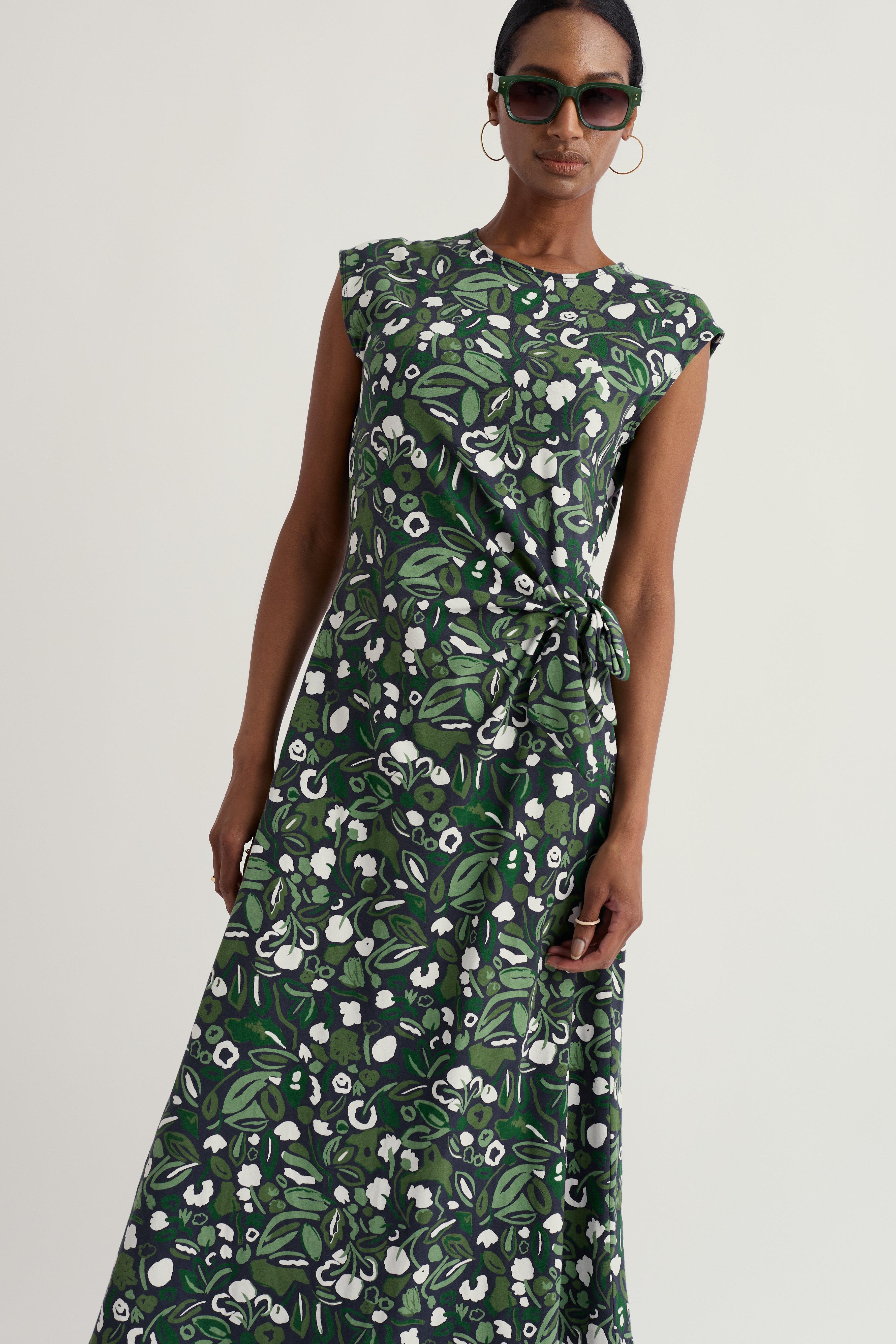 Woman wearing a Seasalt green floral dress on a white background