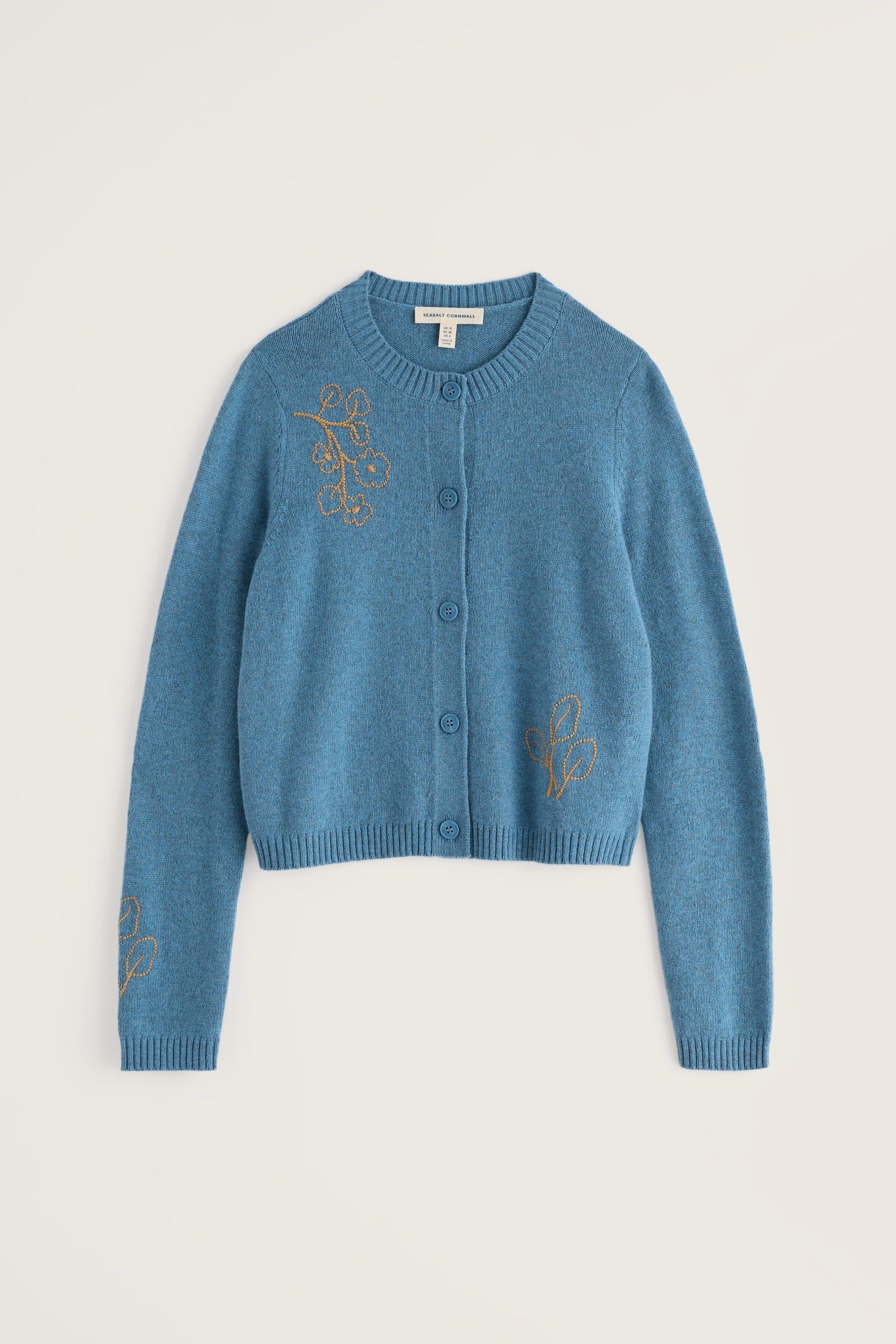 A cropped blue knit cardigan sweater with gold embroidered floral motifs on the chest and sleeves, displayed flat against a light beige background.