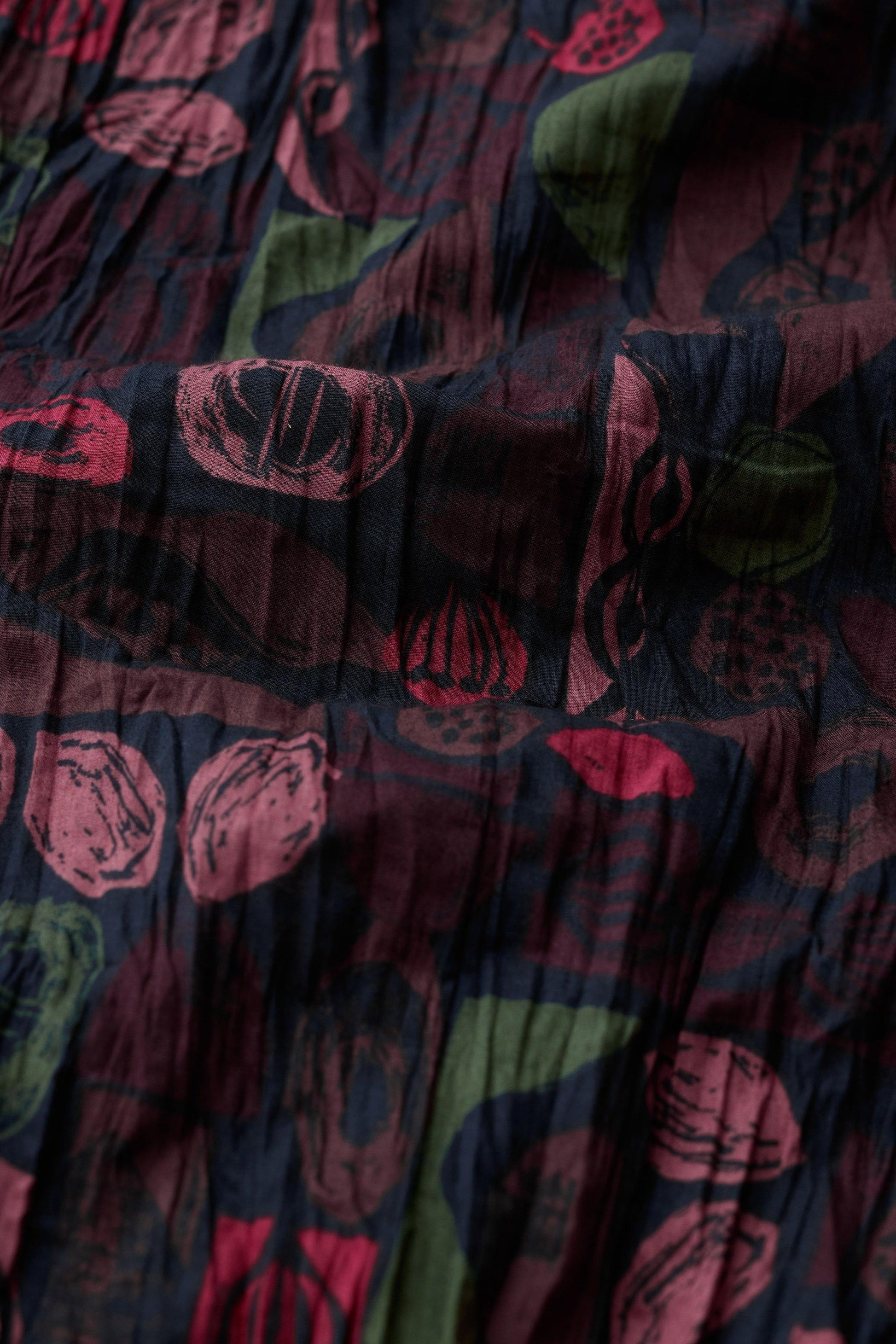 Close up of Seasalt Cornwall organic cotton fabric with a dark floral and fruit print pattern