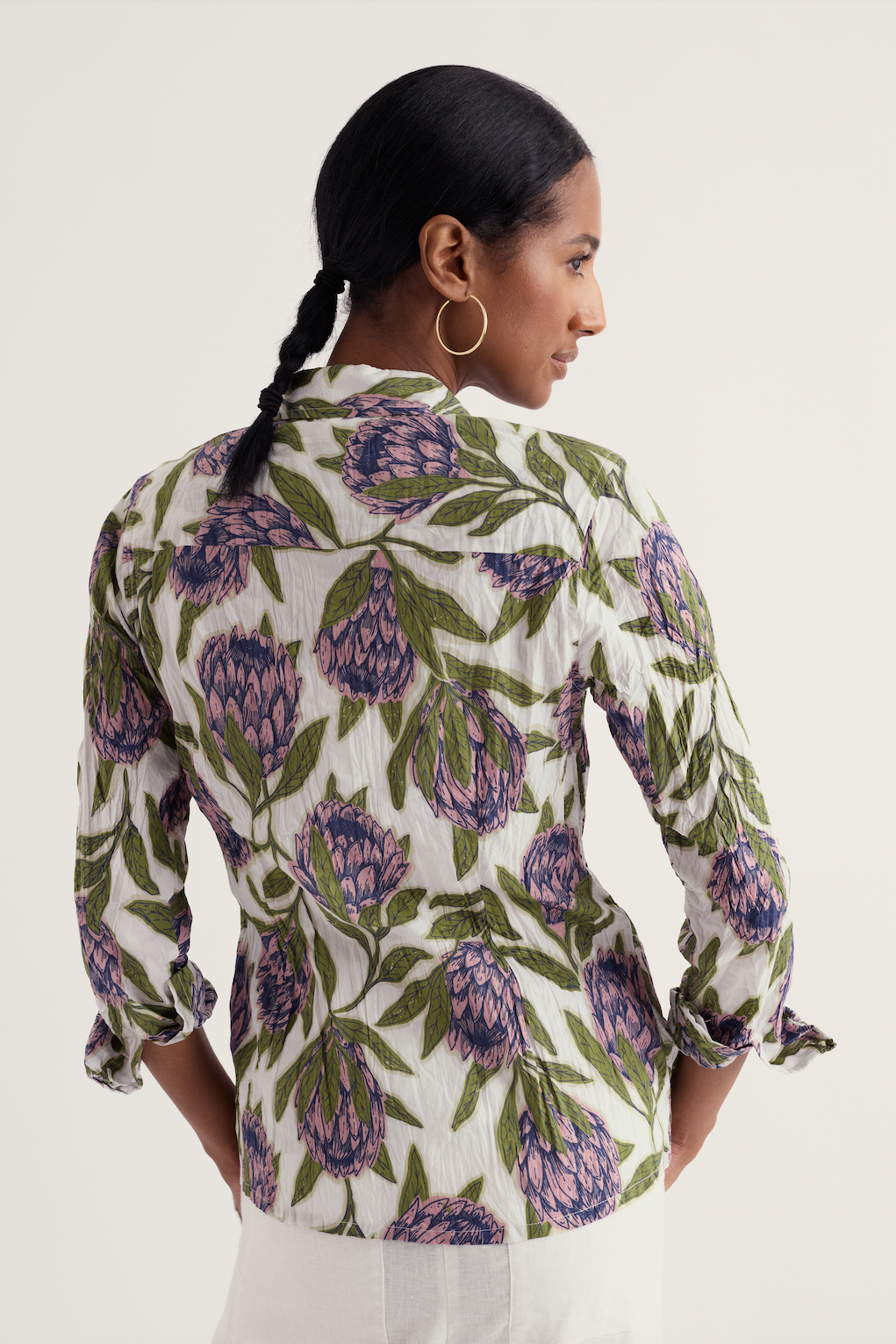 Woman wearing a floral patterned blouse with long sleeves on a white background