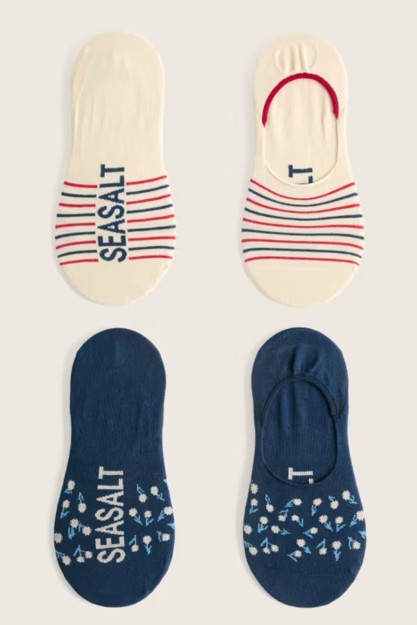 Two pairs of Seasalt no-show socks in striped and floral patterns made from organic cotton on a light background.
