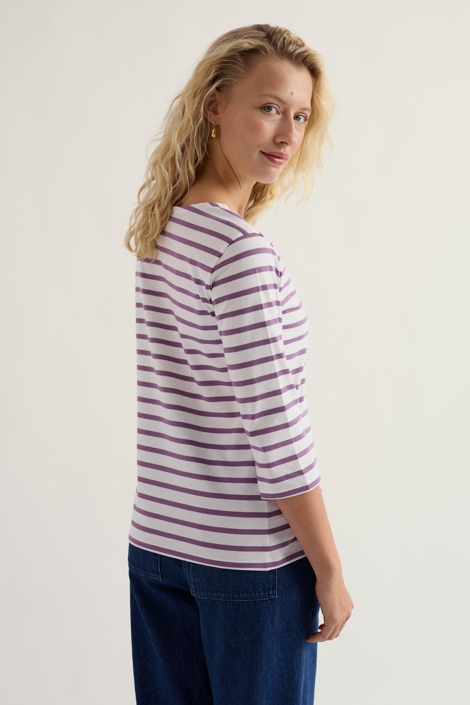 Woman wearing a striped shirt and blue pants on a plain background