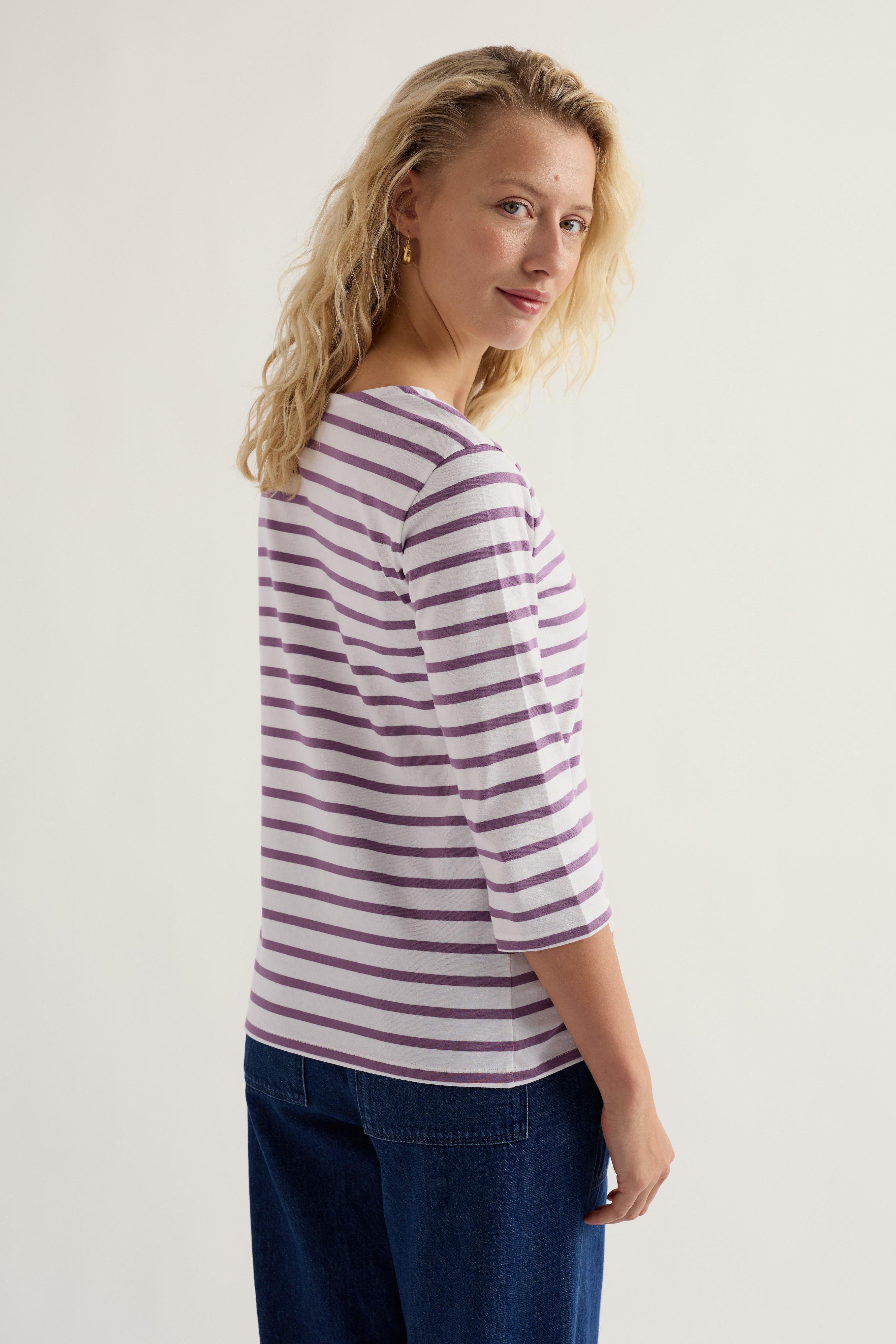 Woman wearing a striped shirt and blue pants on a plain background