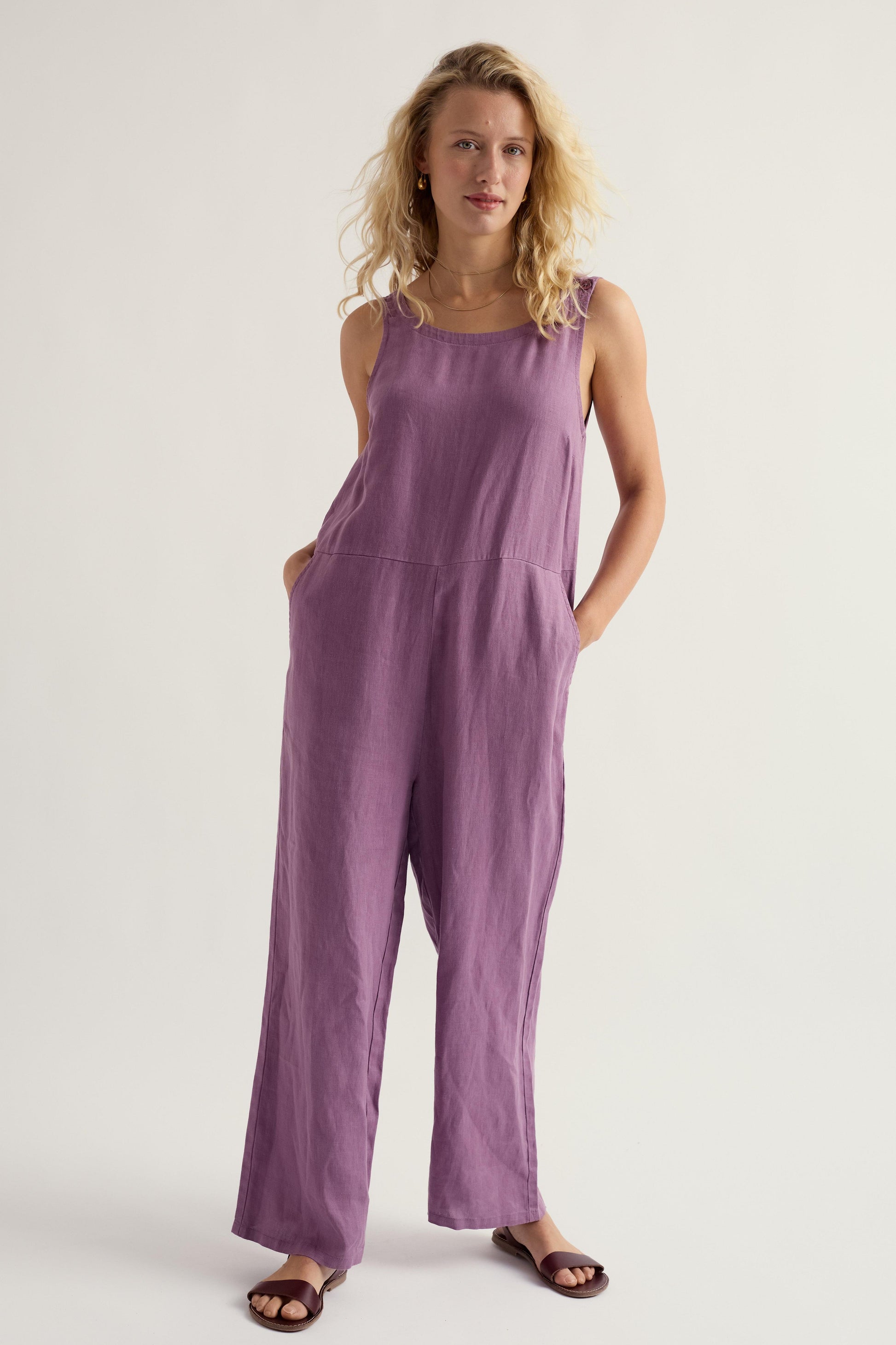 Woman wearing a purple linen jumpsuit on a white background
