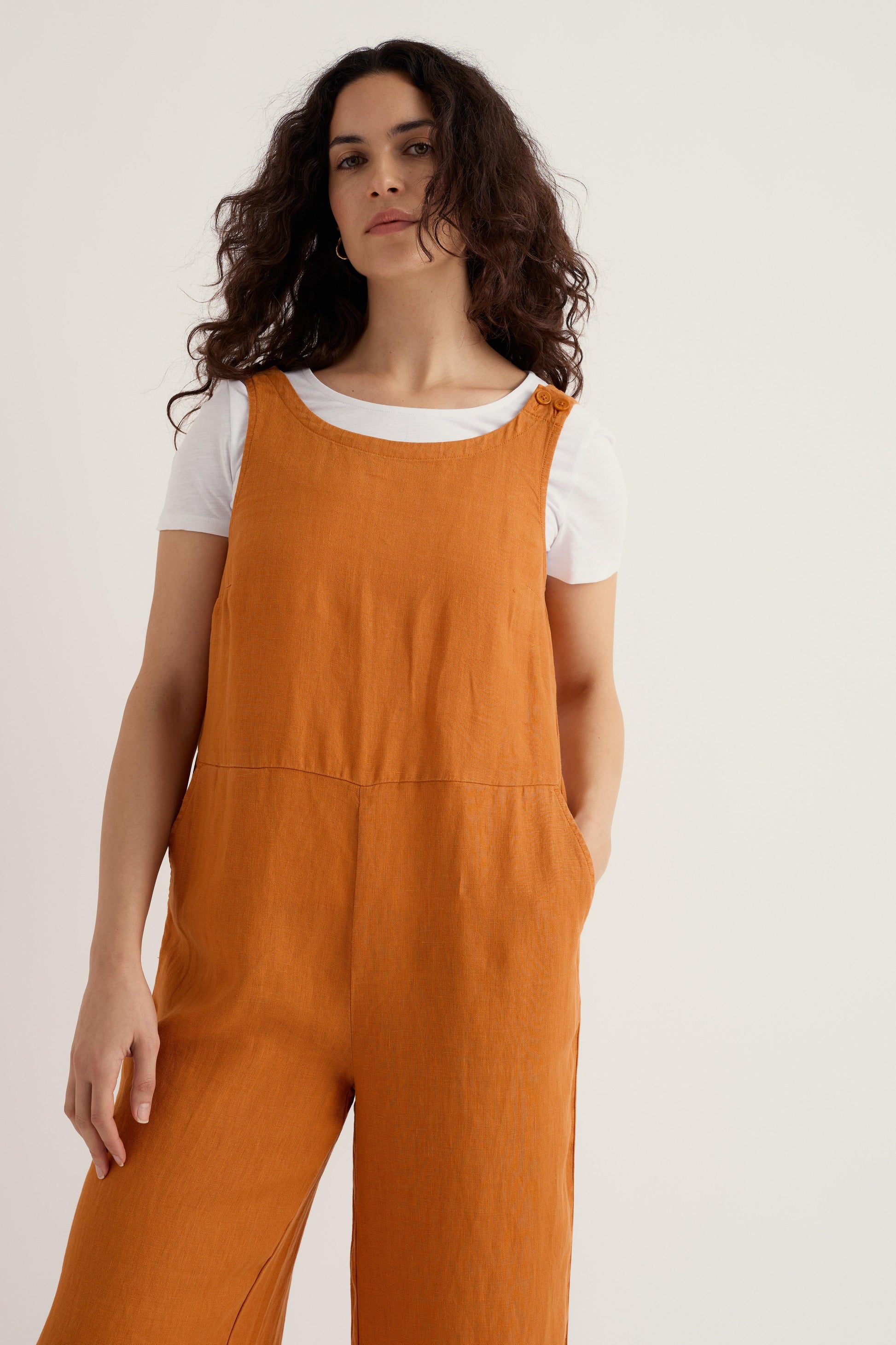 Woman wearing orange overalls on a plain background