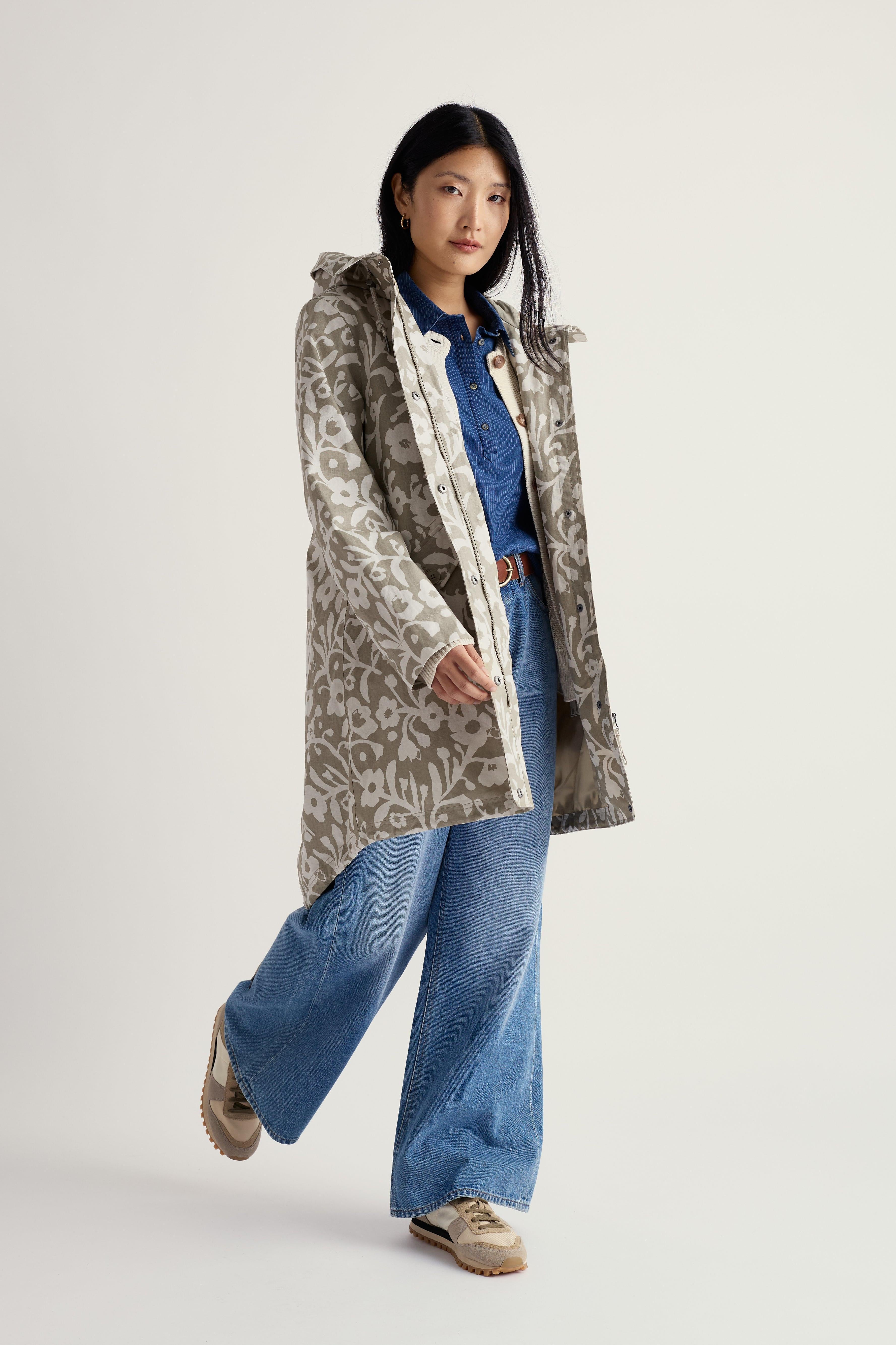 Person wearing a patterned Seasalt coat over a denim outfit on a white background