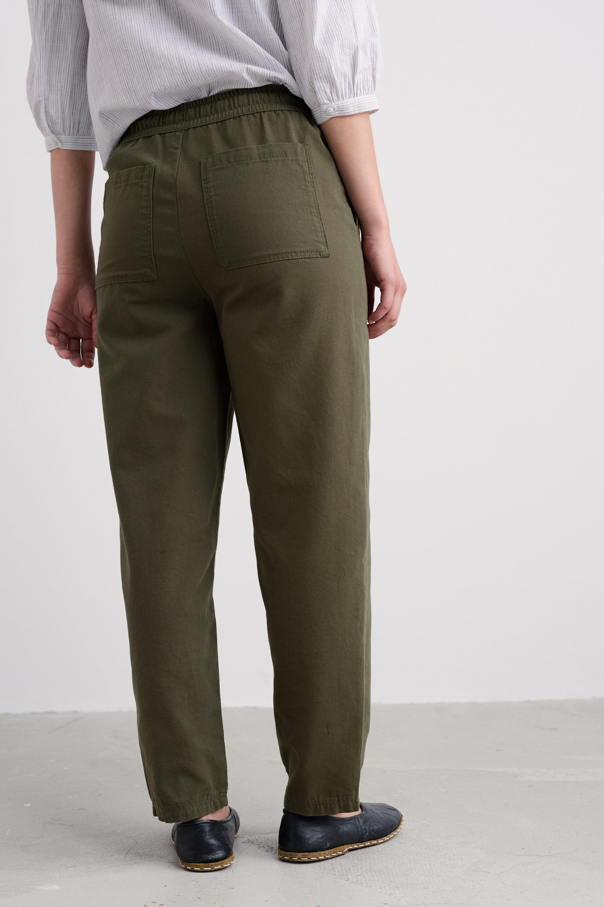 Person wearing olive green pants on a plain background