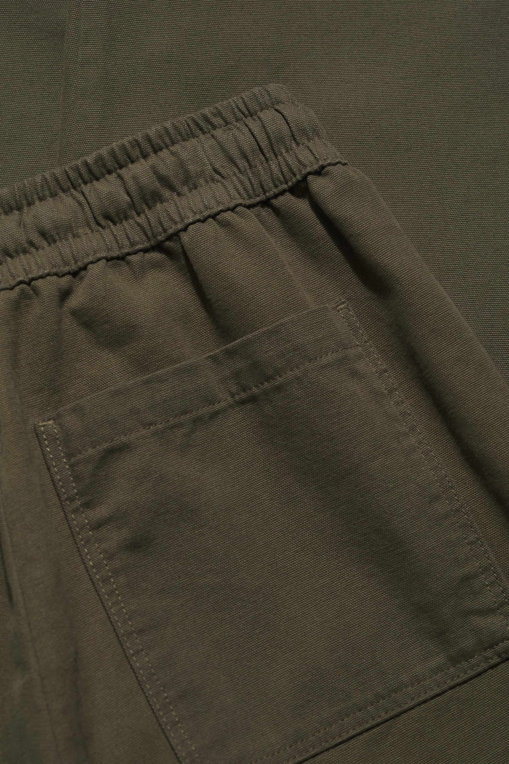 Close-up of olive green pants with an elastic waistband