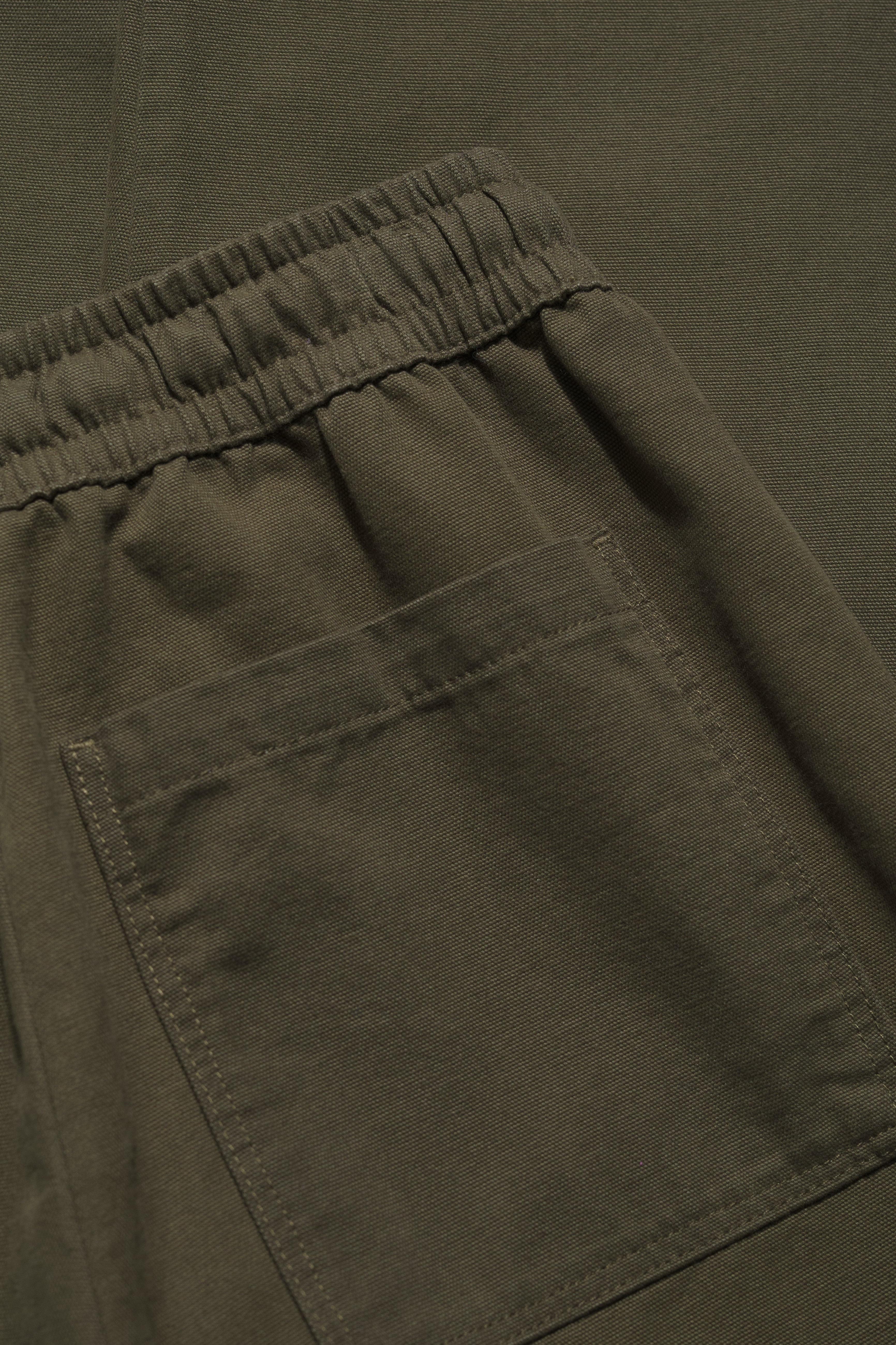 Close-up of olive green pants with an elastic waistband