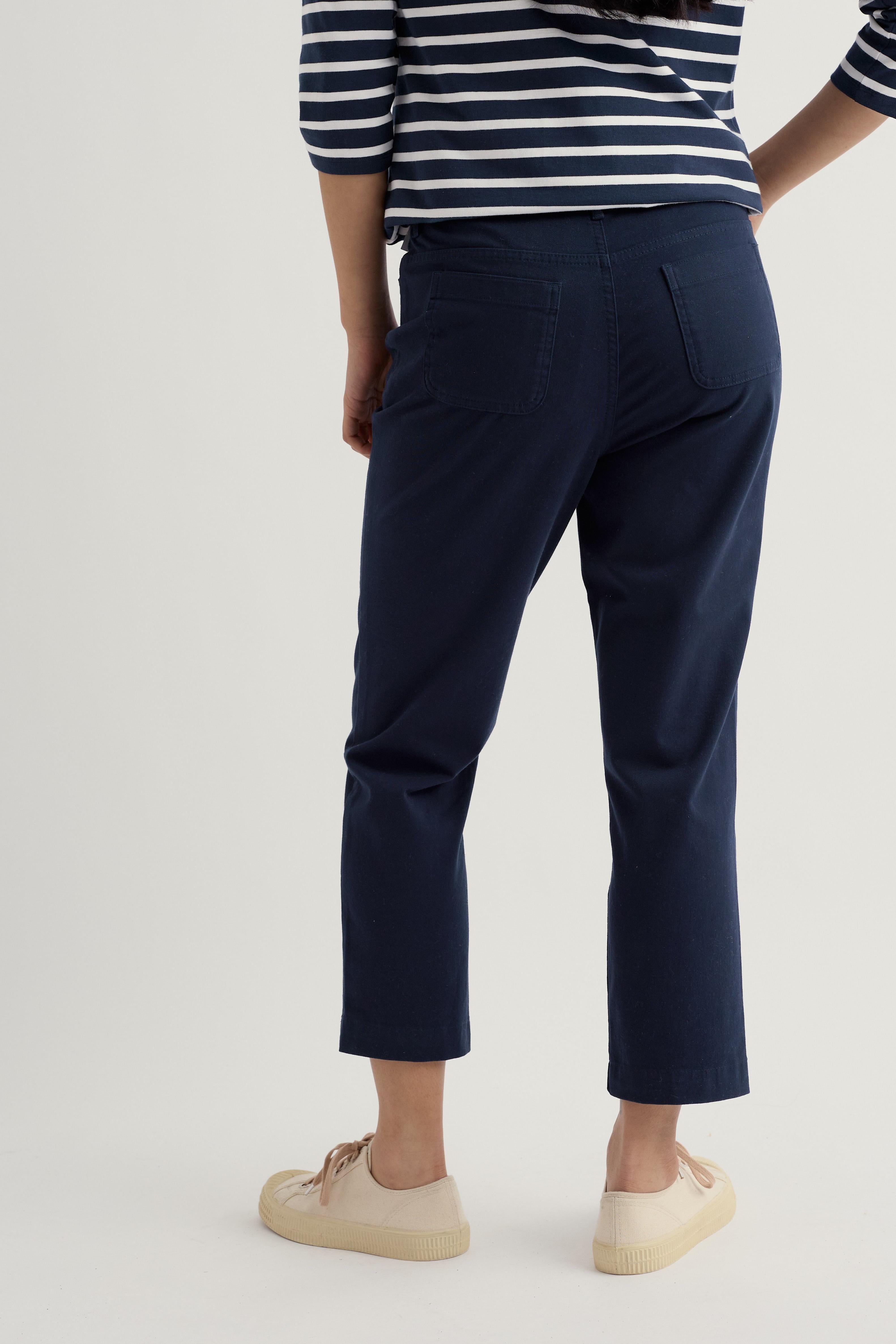 Person wearing navy organic cotton trousers and a striped shirt on a light background