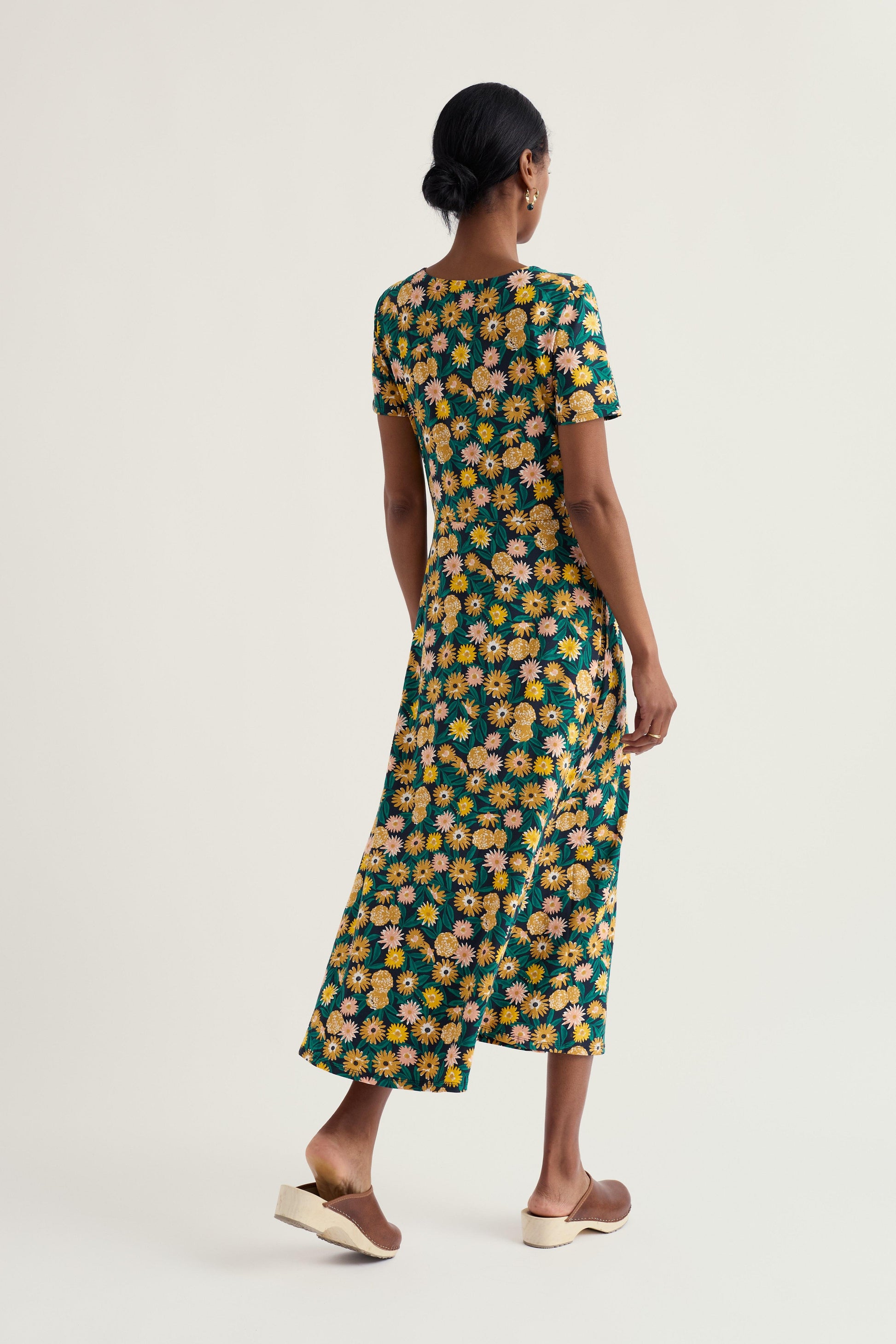 Woman wearing a floral organic cotton dress on a plain background
