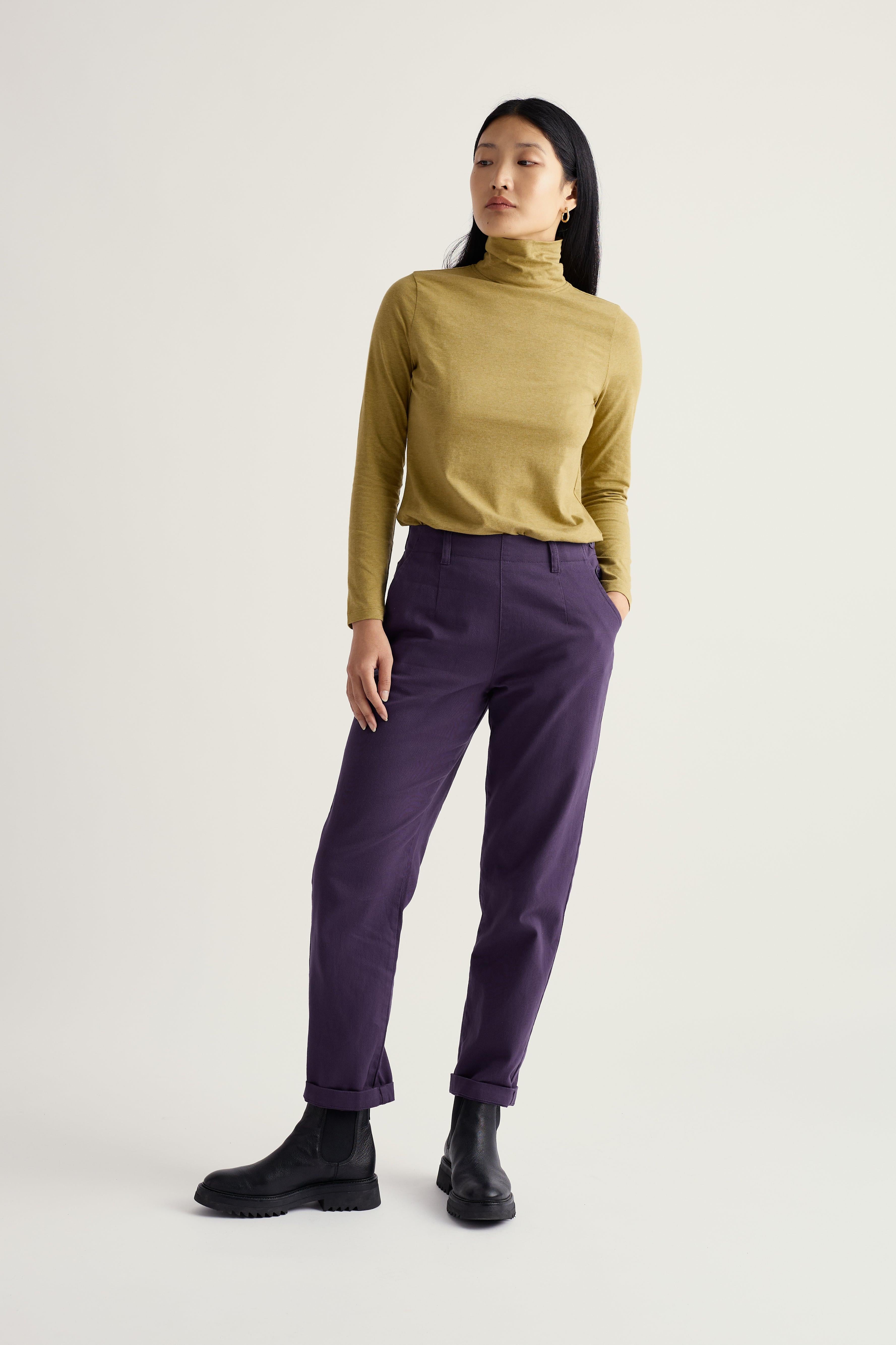 Woman wearing a mustard yellow turtleneck and purple organic cotton pants on a white background