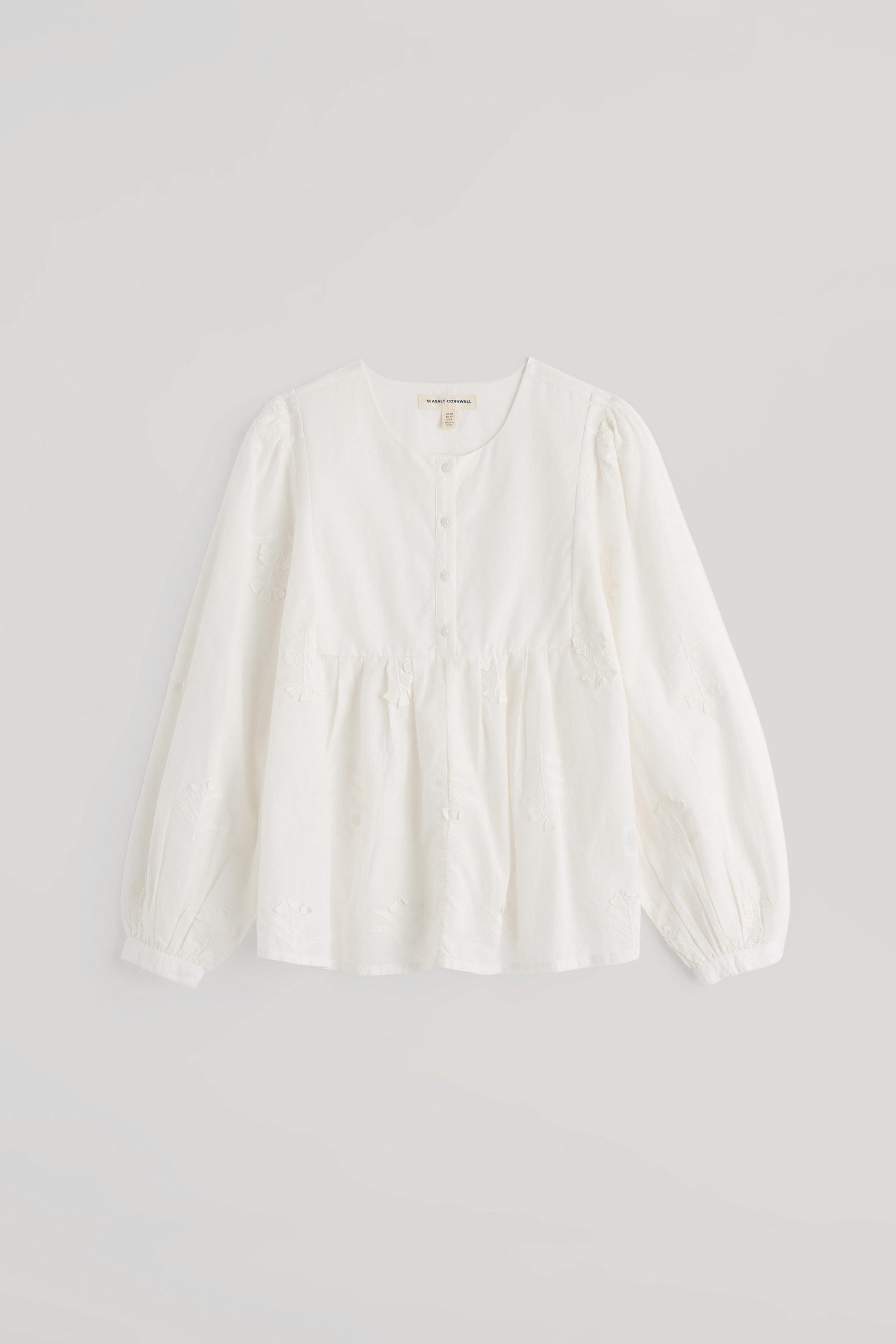 A white long-sleeve blouse with a gathered waist and buttoned neckline, displayed flat against a light gray background.