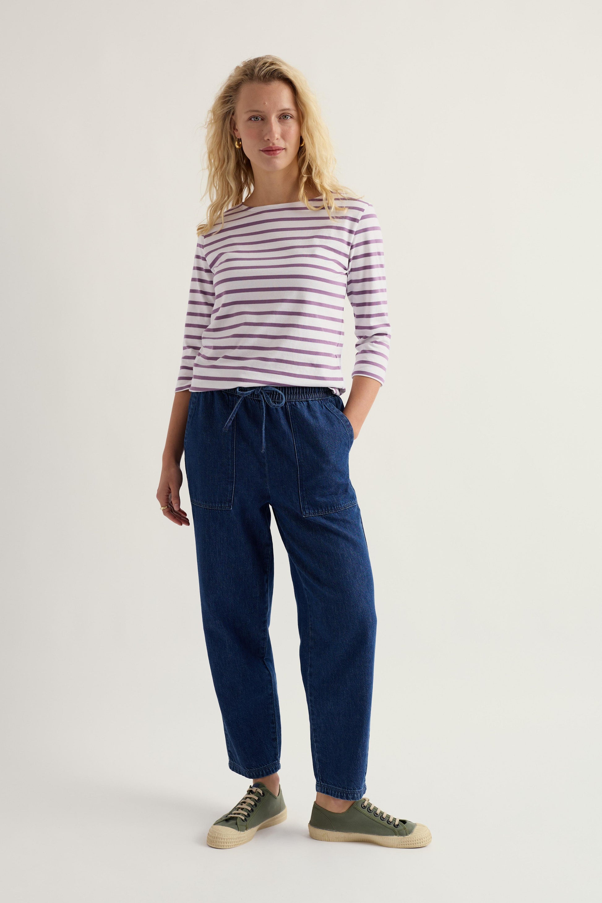 Woman wearing a striped shirt and blue pants on a white background