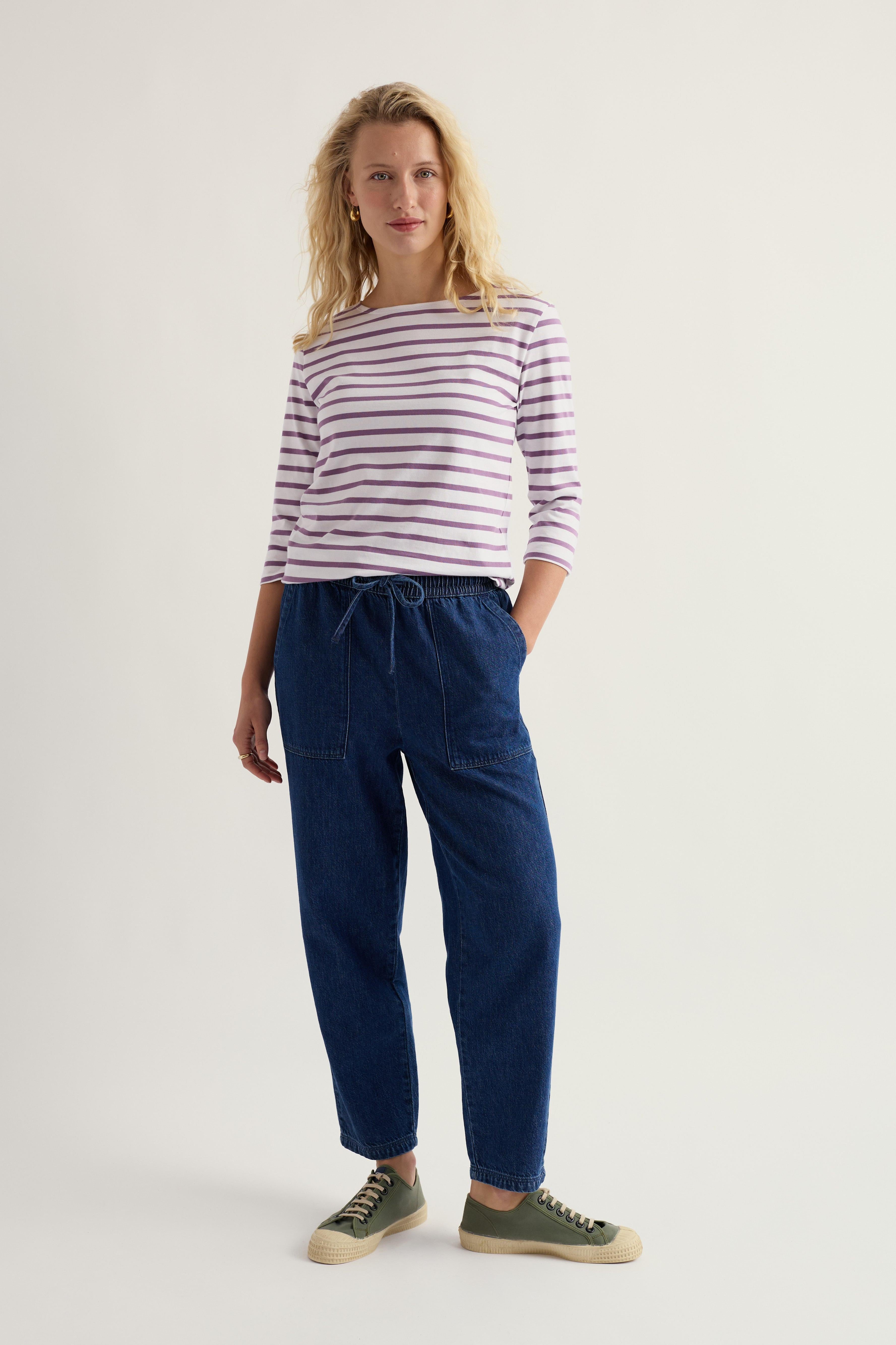 Woman wearing a striped shirt and blue pants on a white background